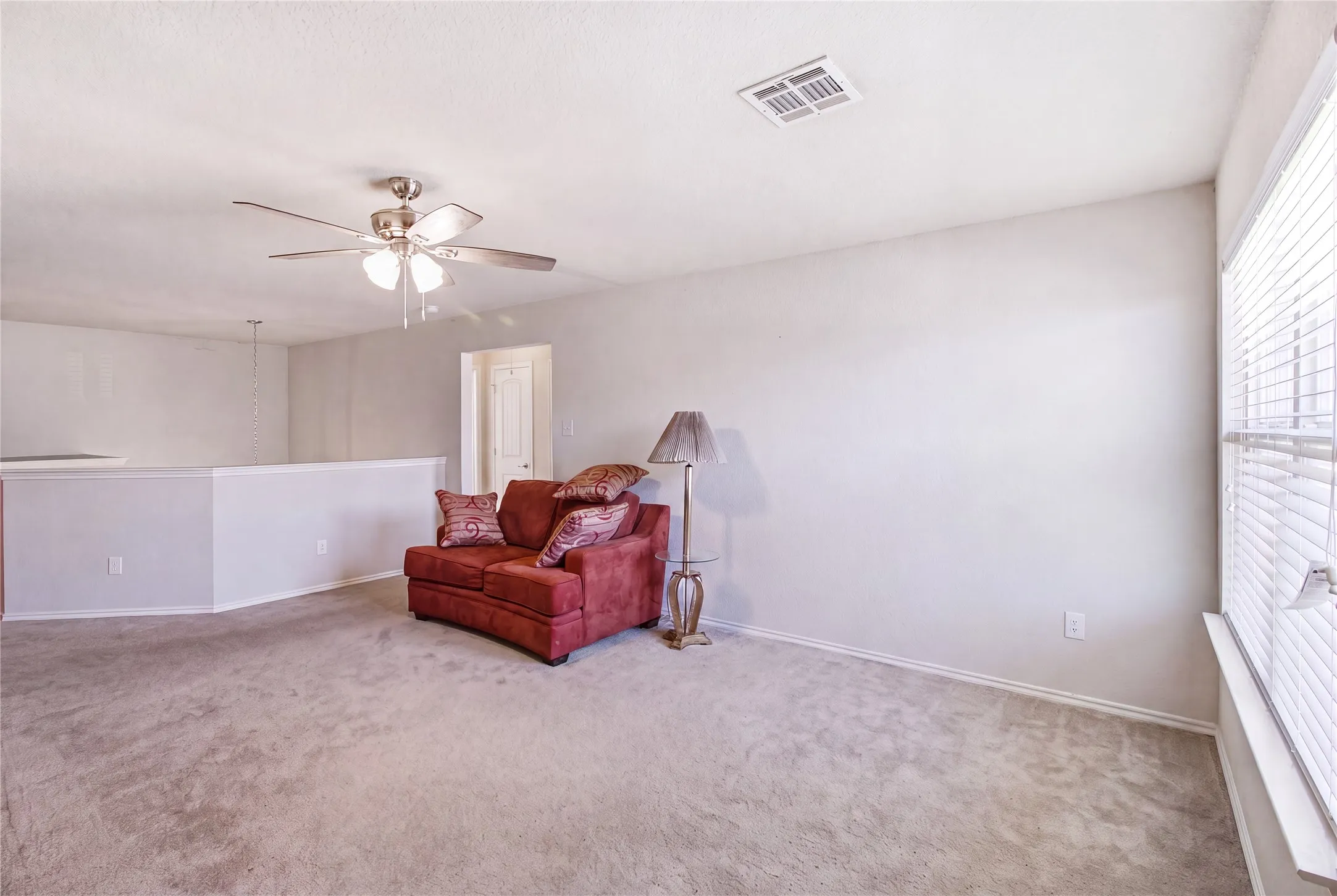 Spacious upper-level area featuring light-colored carpeting and a ceiling fan with integrated lighting