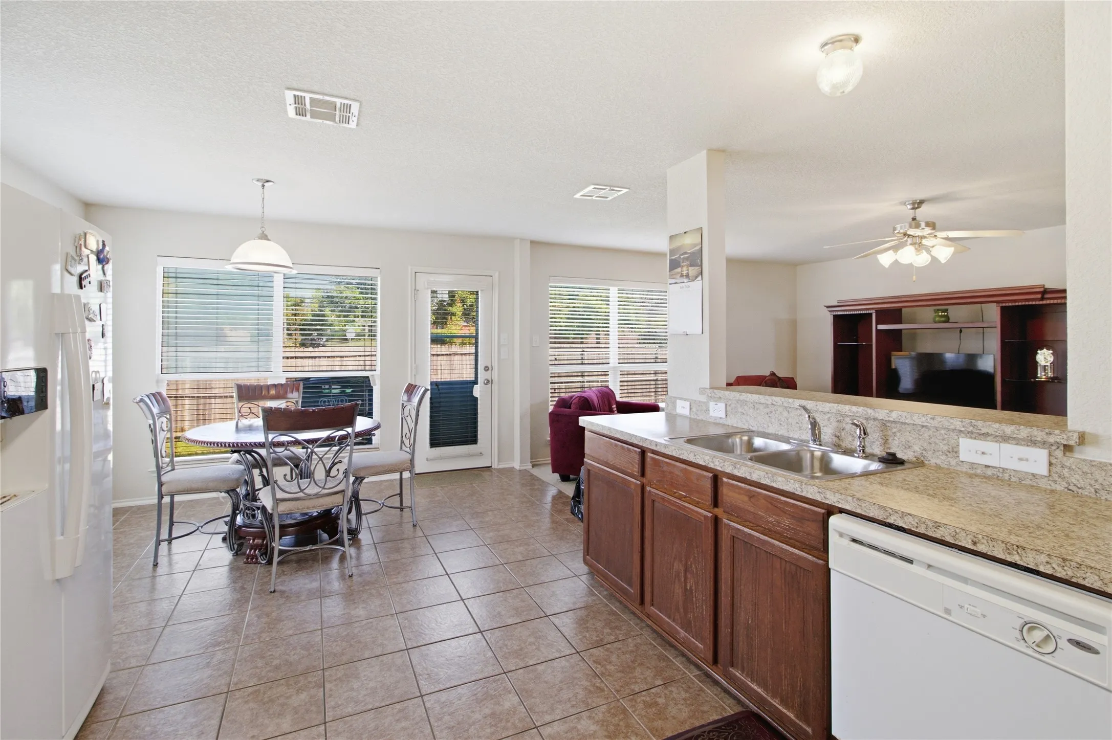 Eat-in kitchen featuring tile flooring, a built-in dishwasher, and wood cabinetry with a light-colored countertop