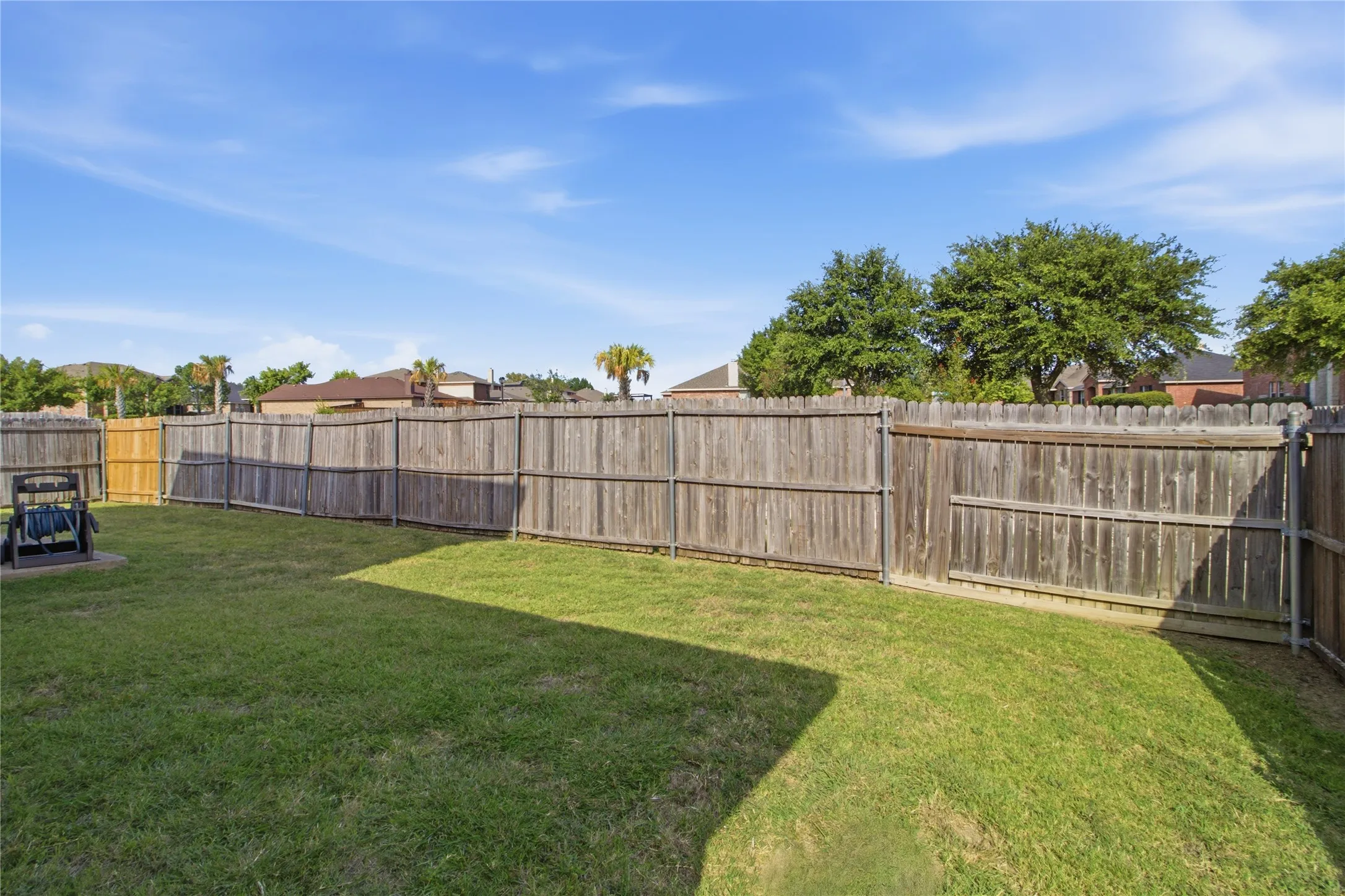 Expansive grassy backyard featuring a wood privacy fence