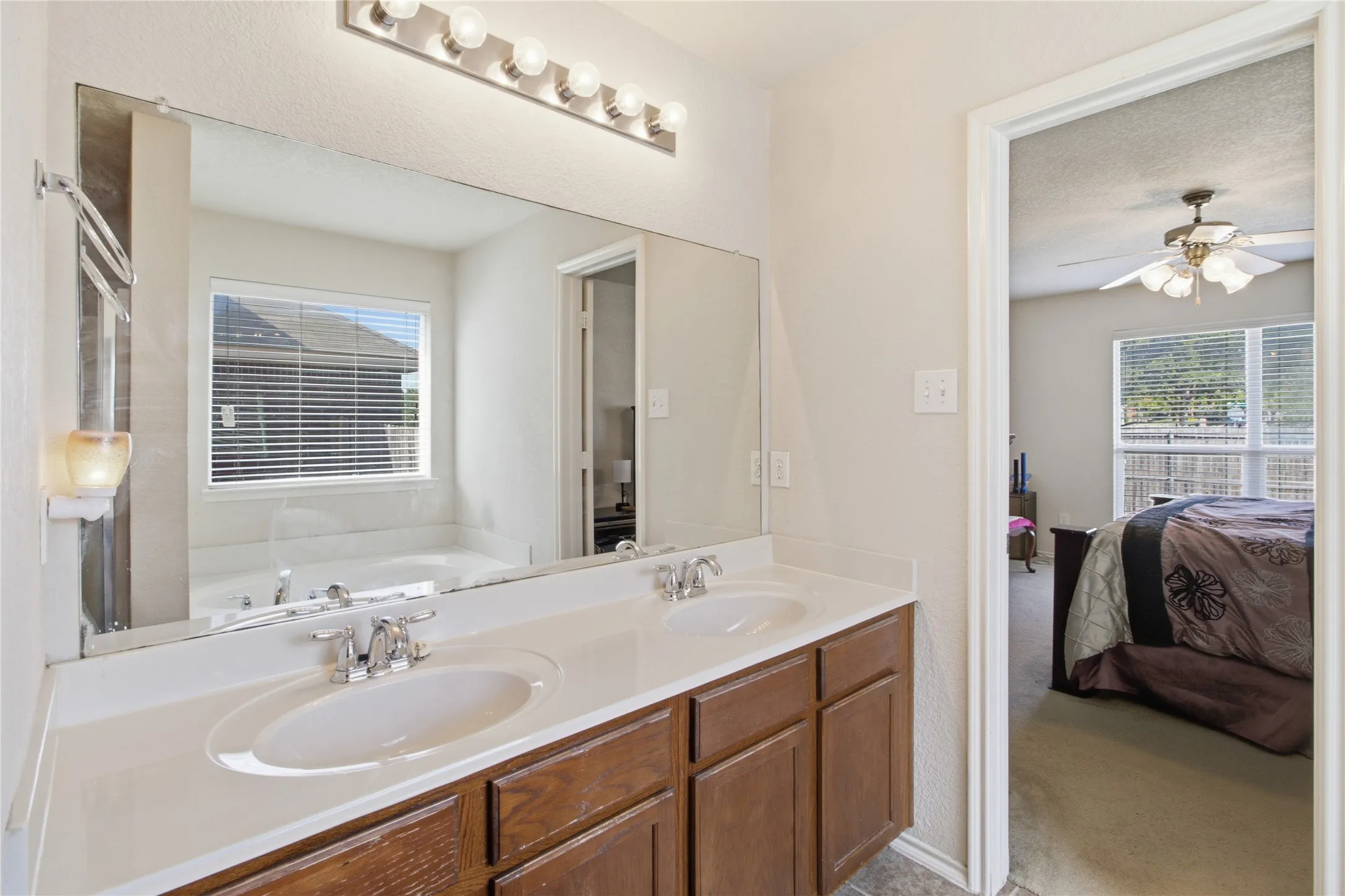 Spacious bathroom featuring a double vanity with ample counter space, chrome fixtures, and wood-finish cabinetry