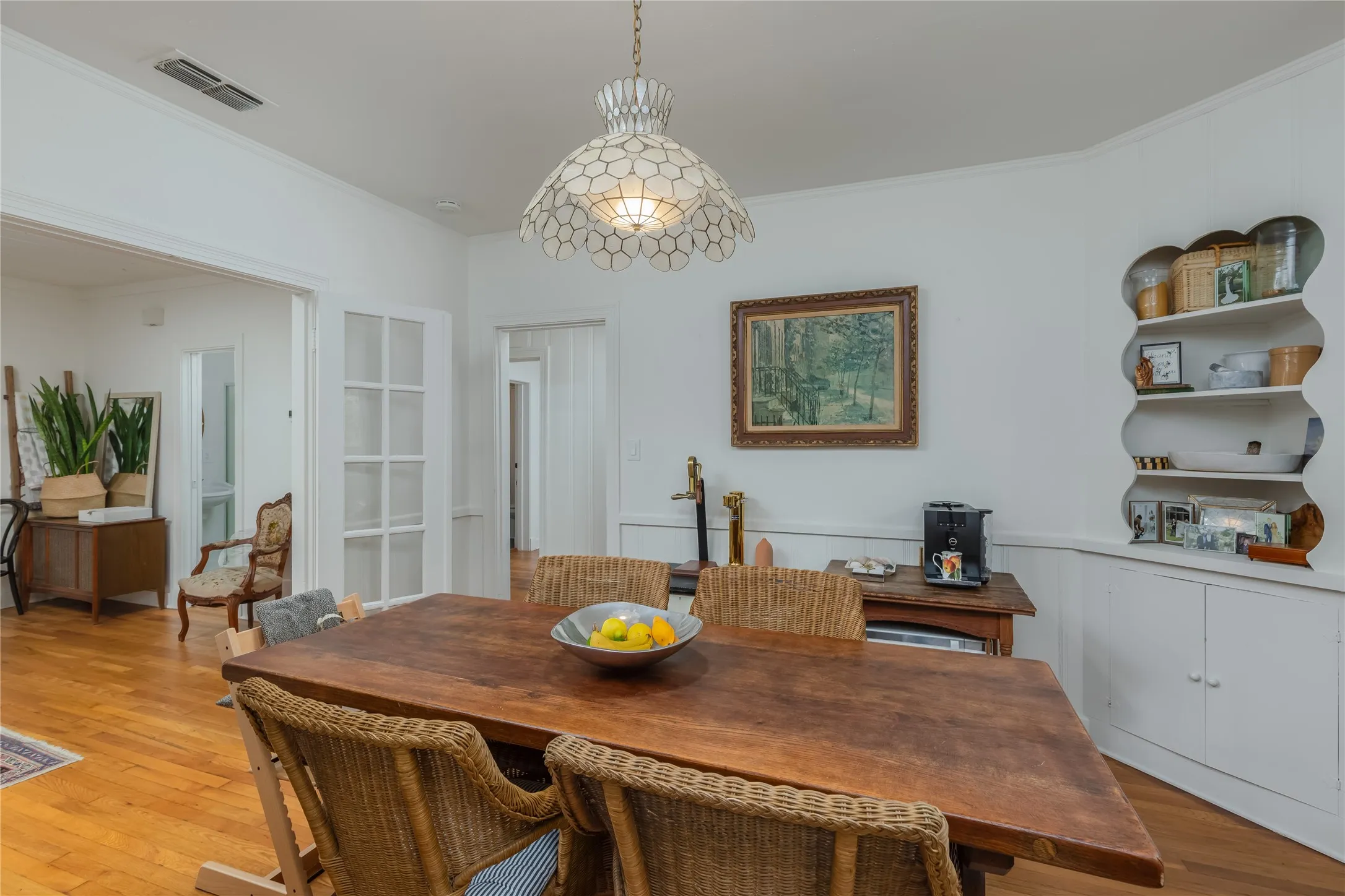 Bright dining space featuring a decorative pendant light fixture, wood-finish flooring, and white paneled walls