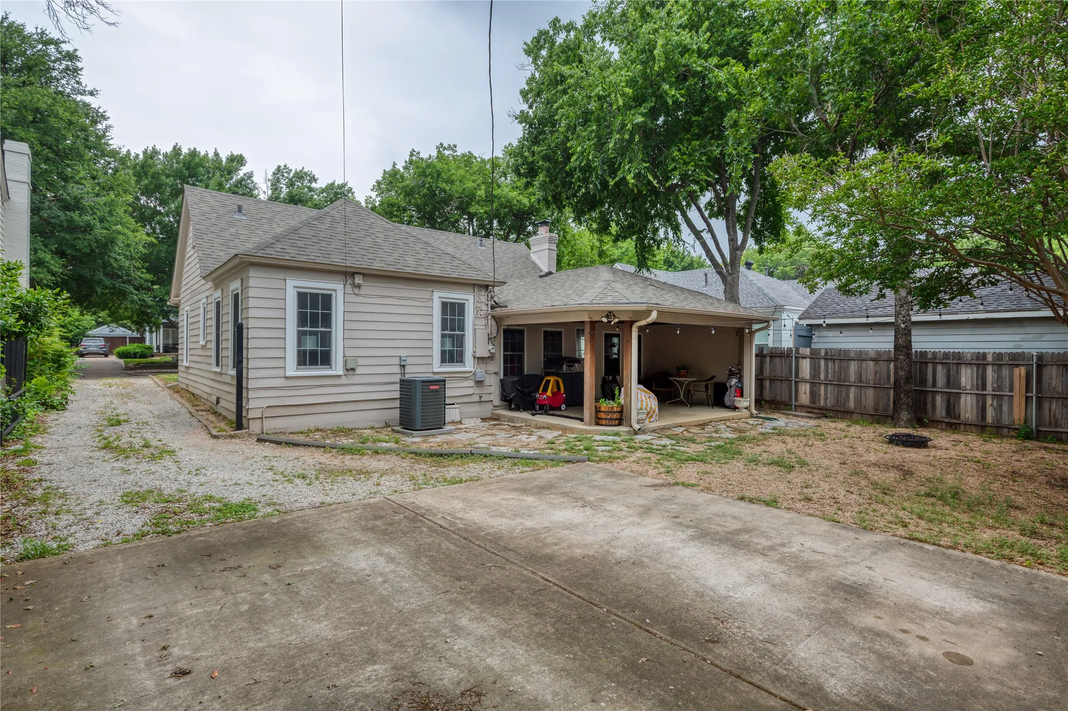 Rear exterior with covered patio, wood fencing, and mature trees