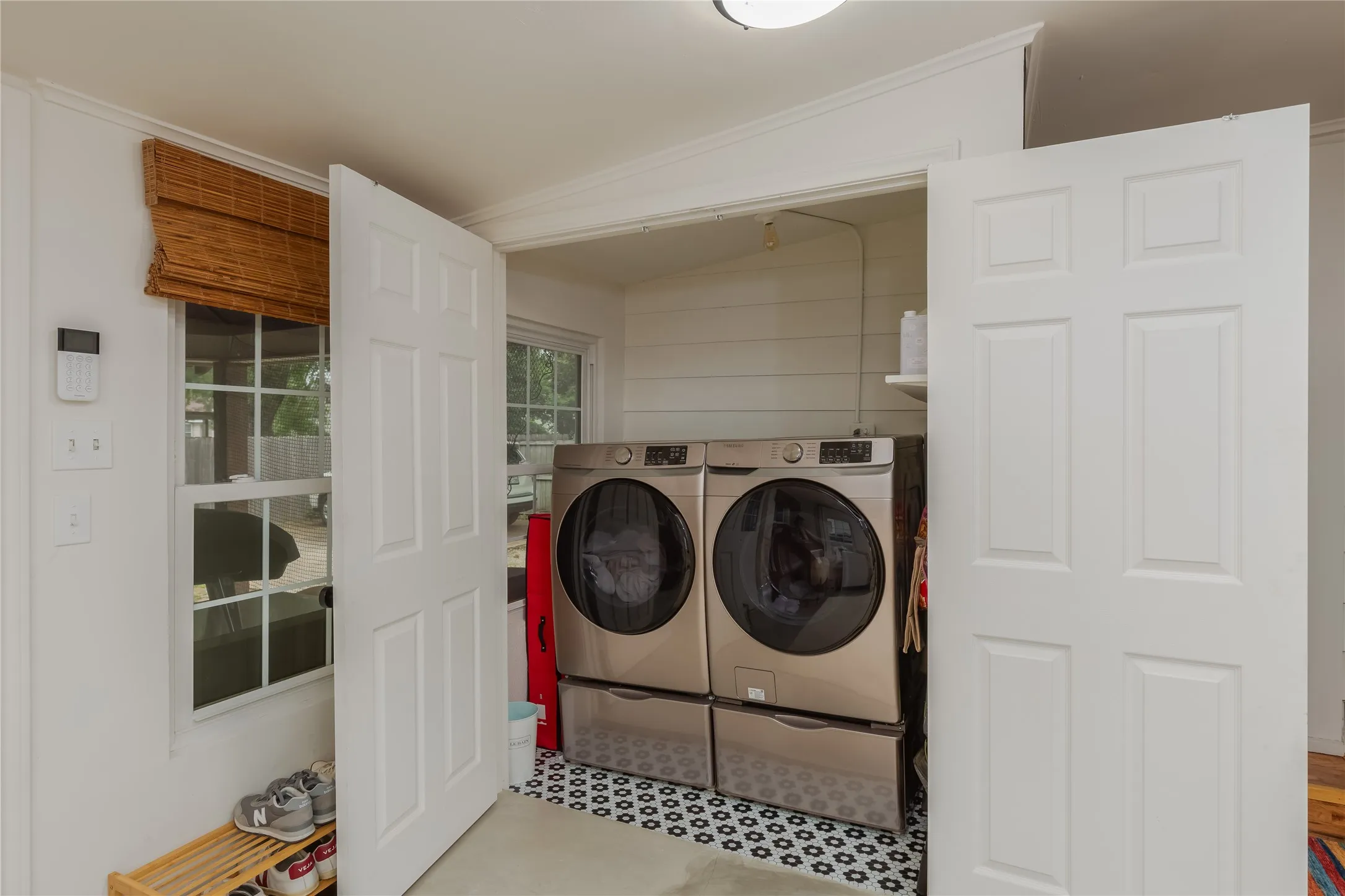 Dedicated laundry area featuring a patterned floor, shiplap-style wall, and a built-in shelf