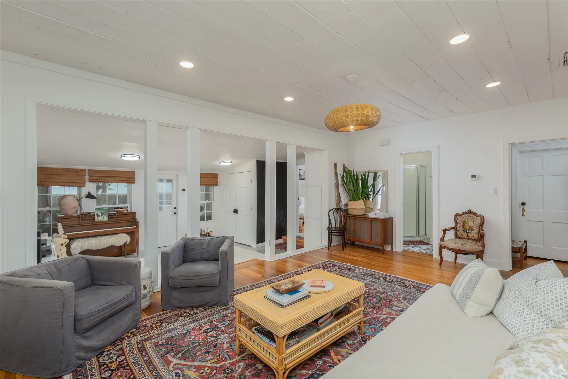 Wood-finish flooring throughout, featuring a white paneled ceiling, recessed lighting, and a woven pendant light fixture