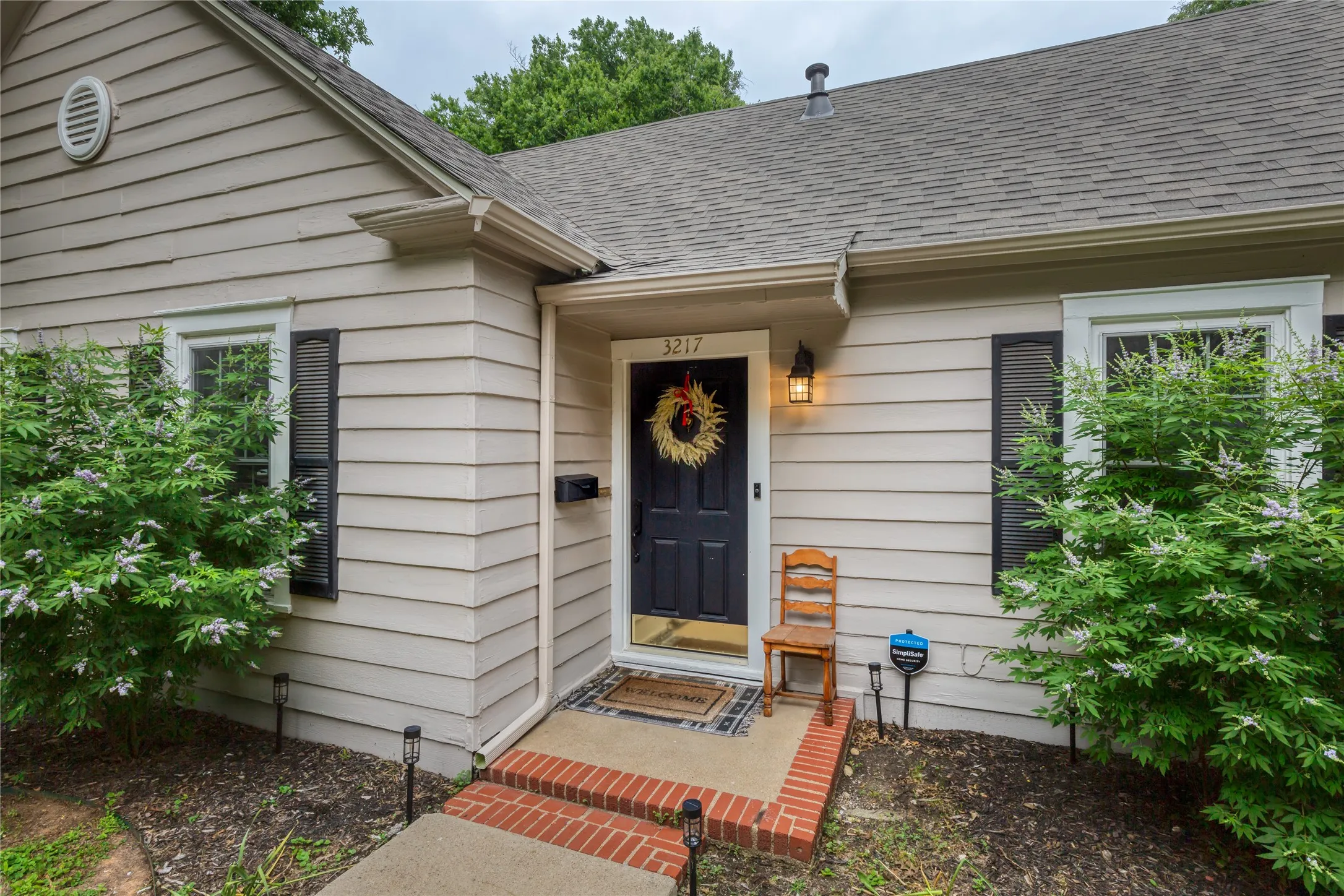 Inviting home exterior featuring horizontal siding, a dark entry door with brass kickplate, and a porch light