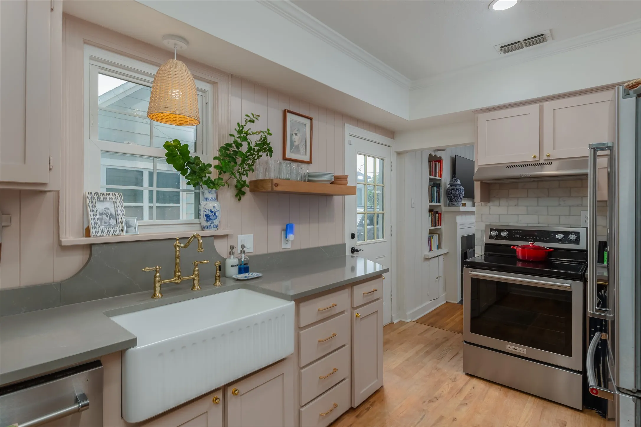 Kitchen featuring a white farmhouse sink with brass fixtures, light grey countertops, and light wood-finish flooring