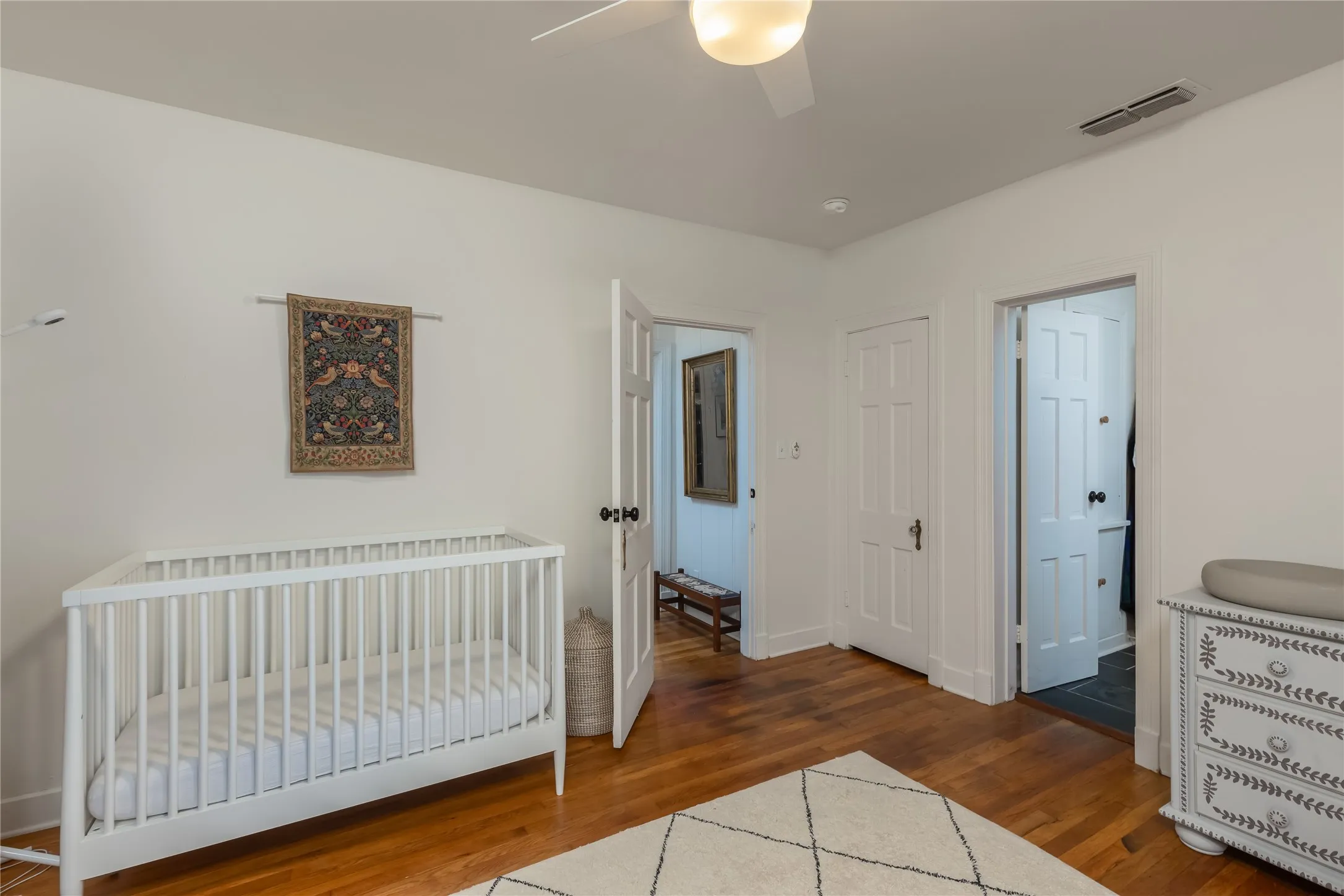 Hardwood flooring throughout, featuring paneled interior doors and a ceiling fan with integrated lighting