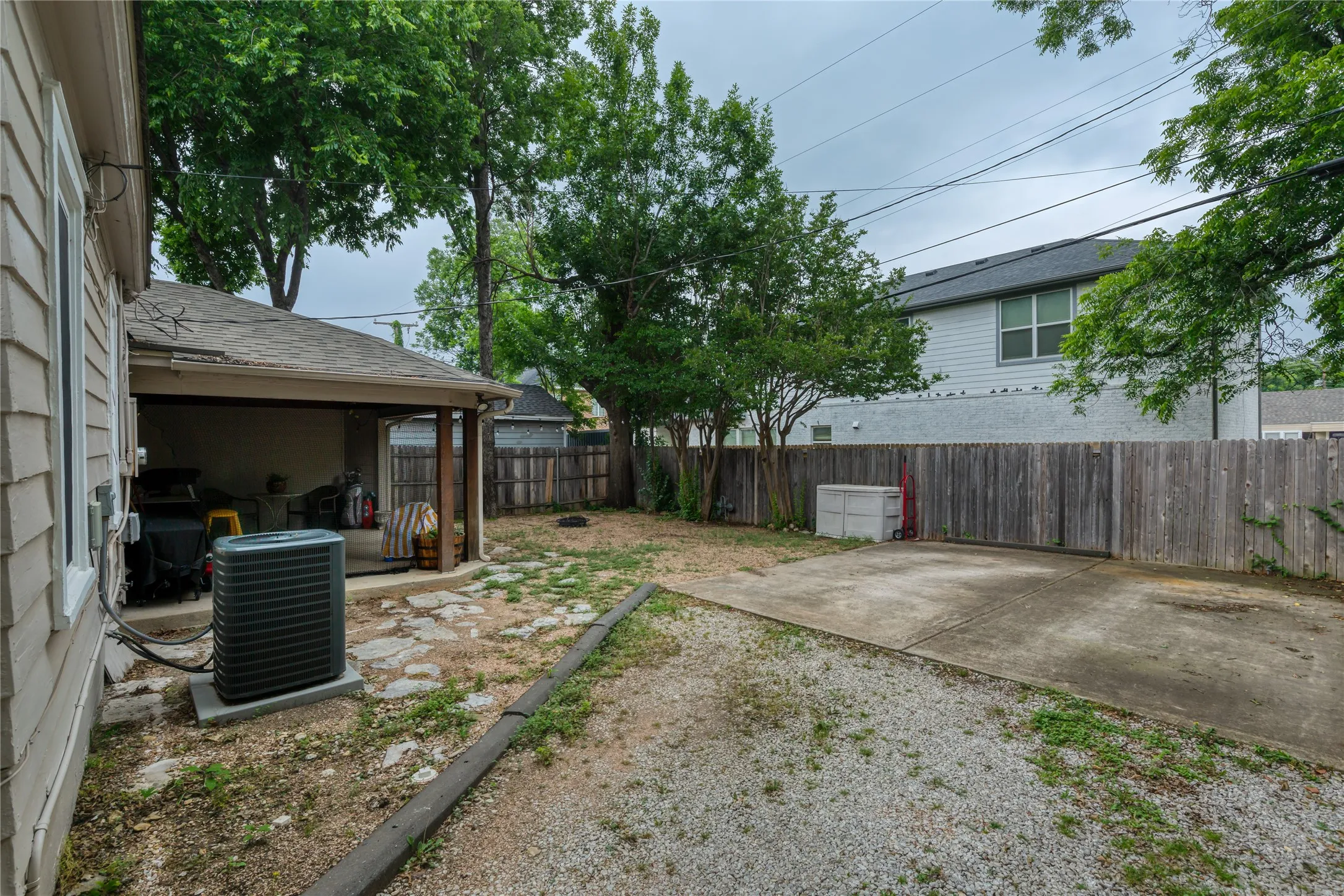 Expansive rear yard featuring a gravel surface, wood privacy fencing, and mature trees