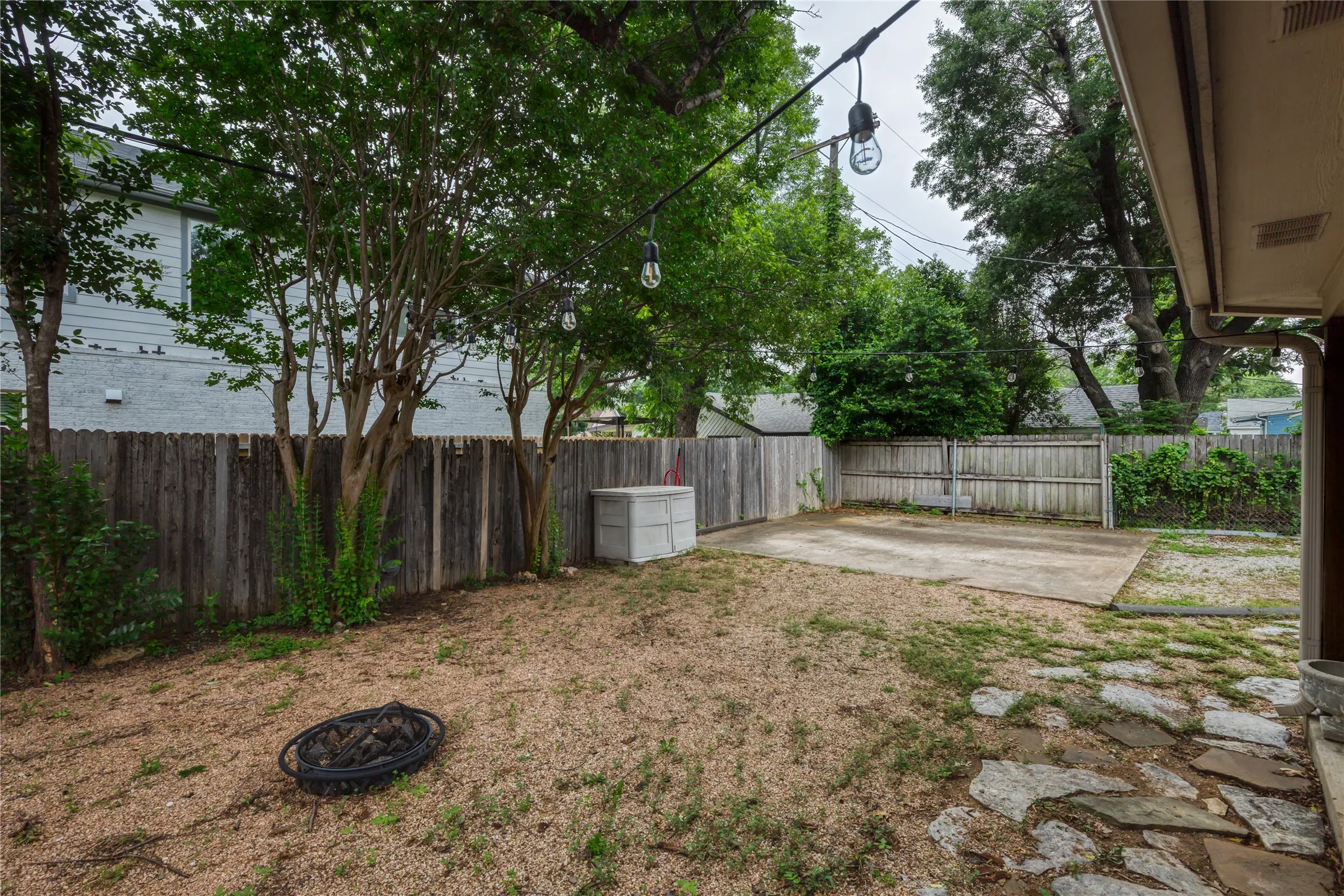 Outdoor area featuring a stone patio, gravel ground cover, and string lighting