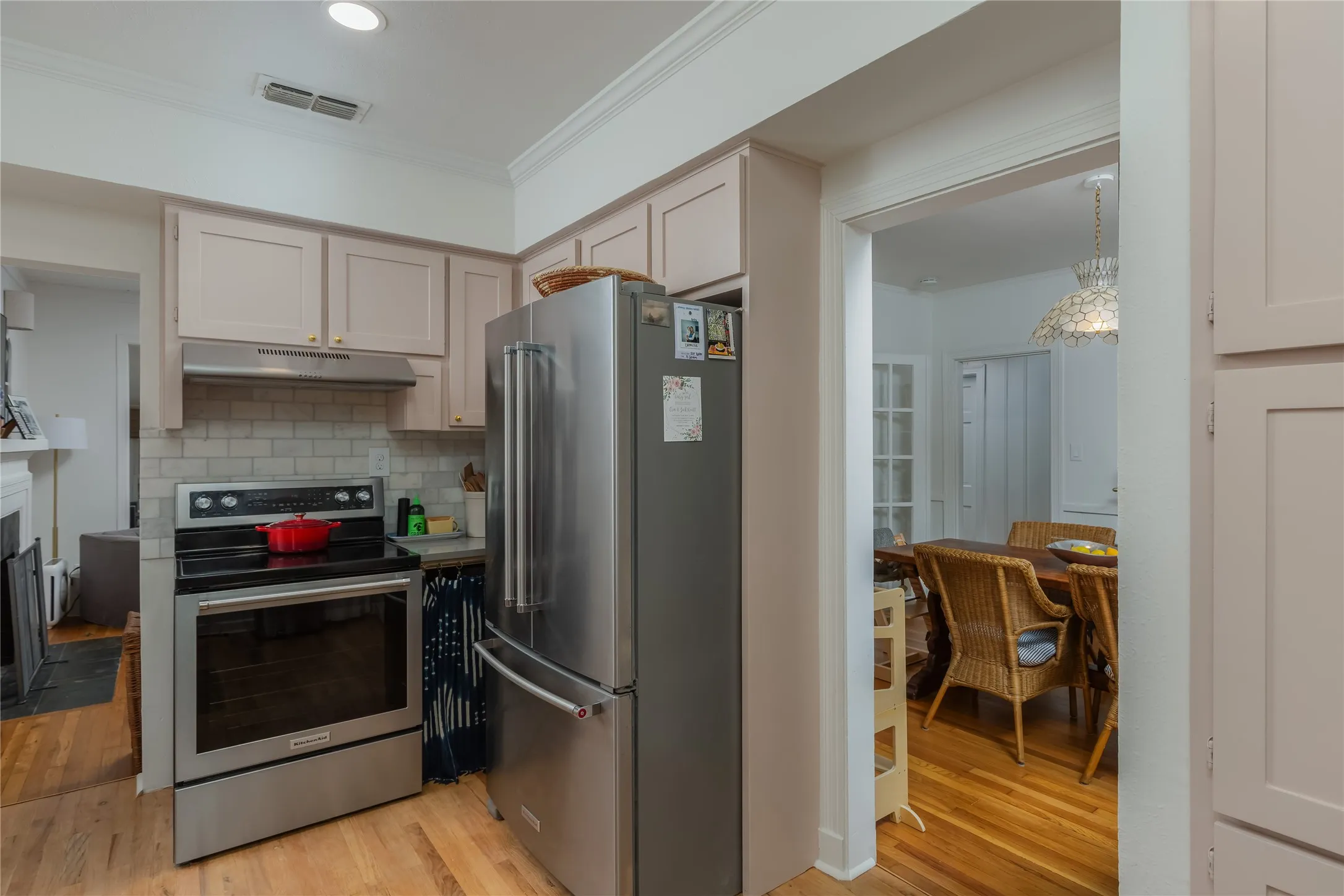 Kitchen featuring light-toned cabinetry, stainless steel appliances, subway tile backsplash, and wood-finish flooring