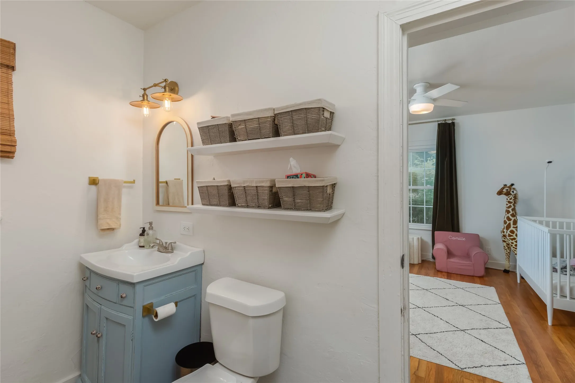 Compact bathroom featuring a corner vanity with a light blue finish, white countertop, and brass hardware
