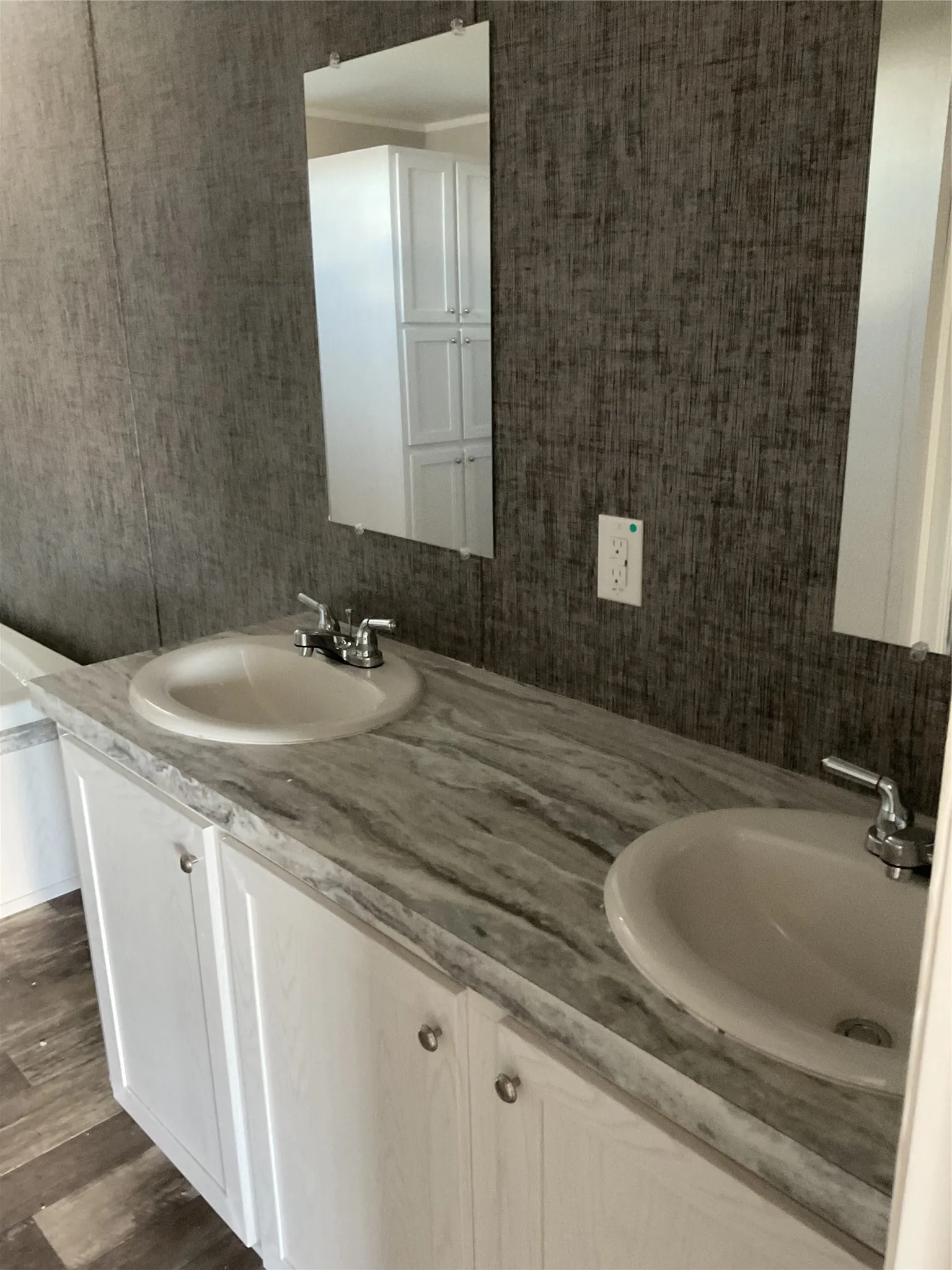 Double vanity featuring white cabinetry with silver-toned hardware, two integrated sinks, and a marbled countertop