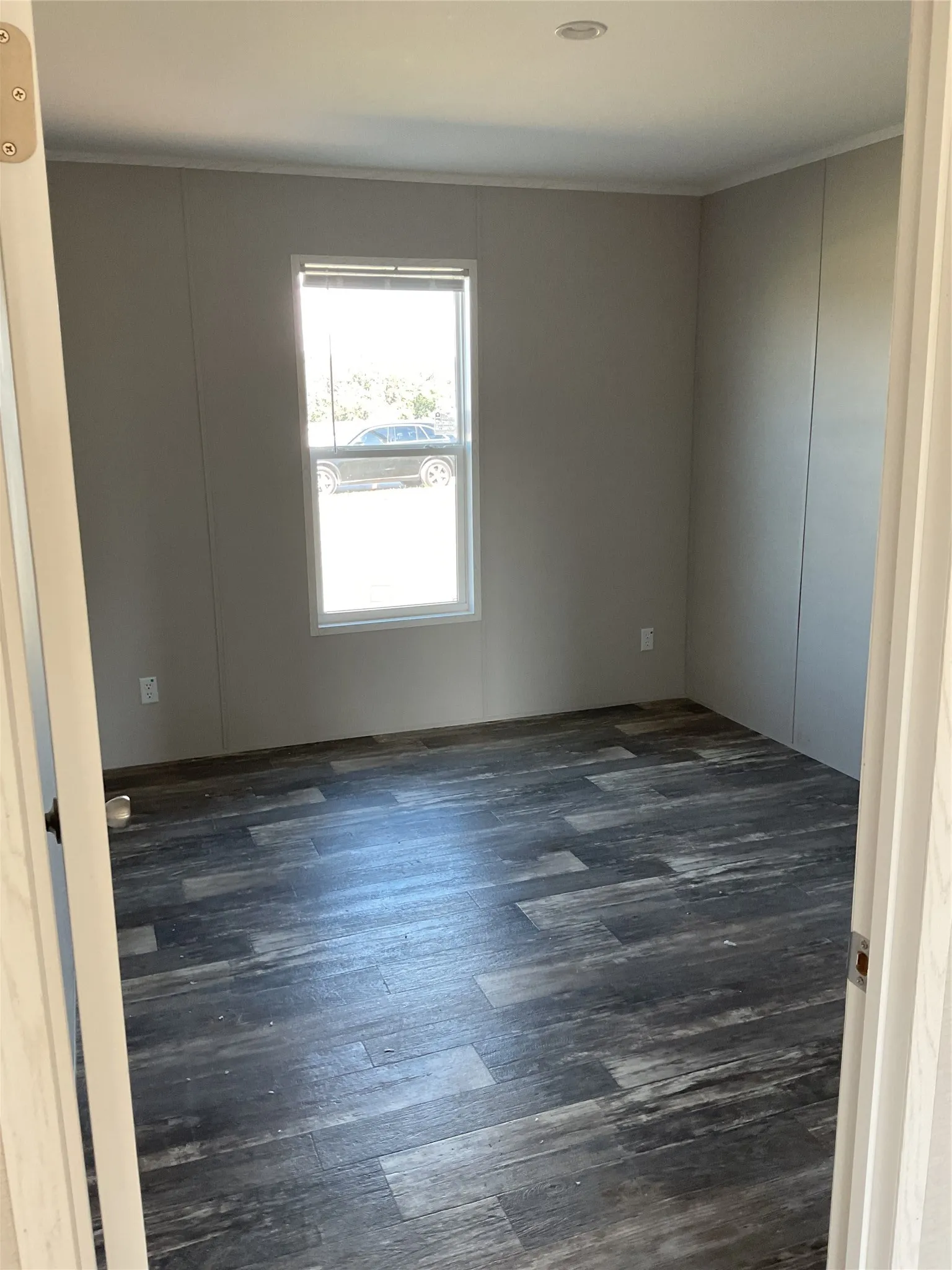 Room featuring wood-finish flooring, a single window, and neutral-toned walls