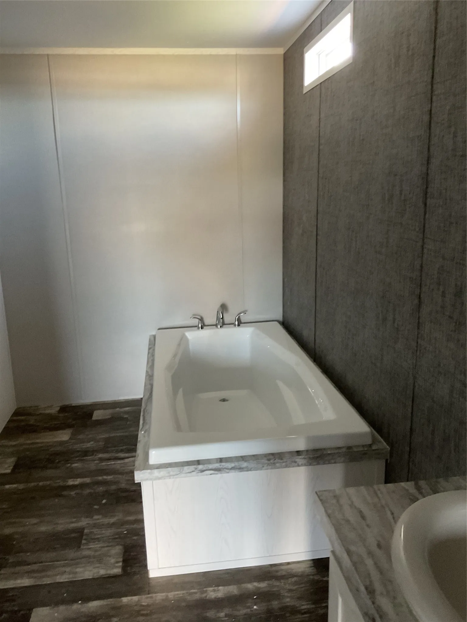 White soaking tub with chrome fixtures, set against a dark wood-finish flooring