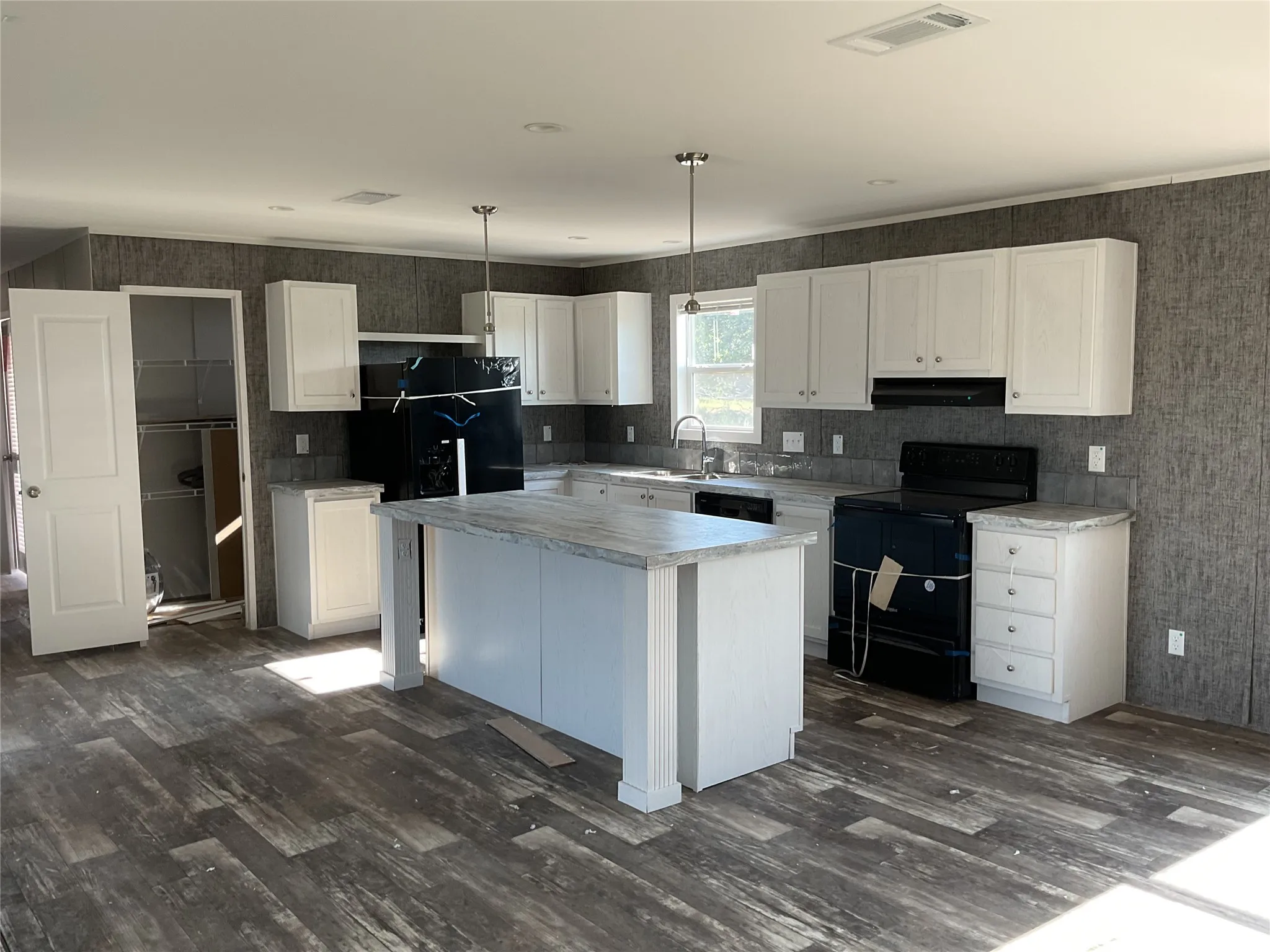 Modern kitchen featuring white cabinetry, a center island with countertop, black appliances, and wood-finish flooring