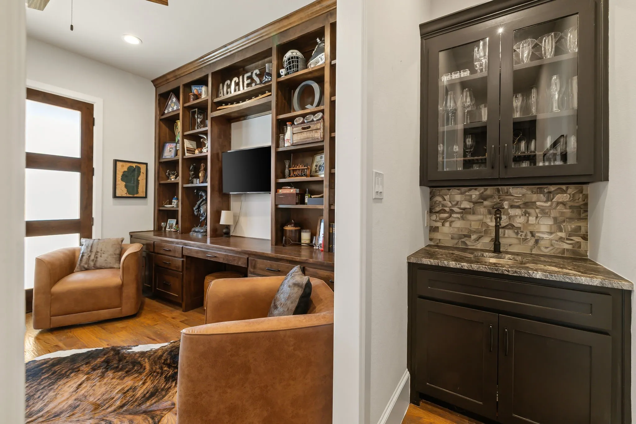 Integrated wet bar featuring dark cabinetry, stone backsplash, and an sink.