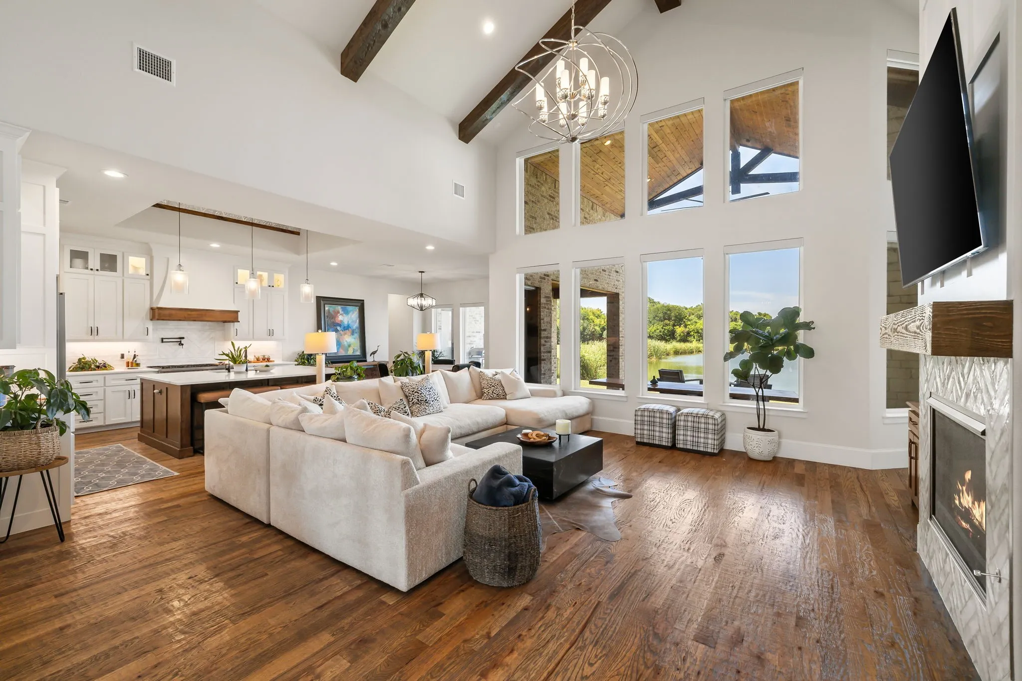 Spacious living area featuring high vaulted ceilings with exposed wood beams, a prominent fireplace with a mosaic tile surround, and extensive wood-finish flooring