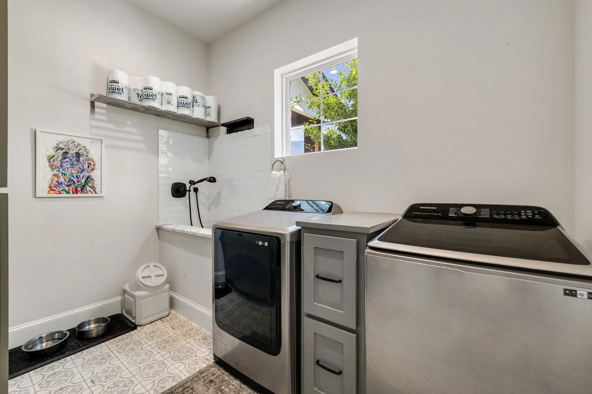 Dedicated utility space featuring a built-in pet wash station with white subway tile backsplash, a matte black handheld shower fixture, and a floating shelf