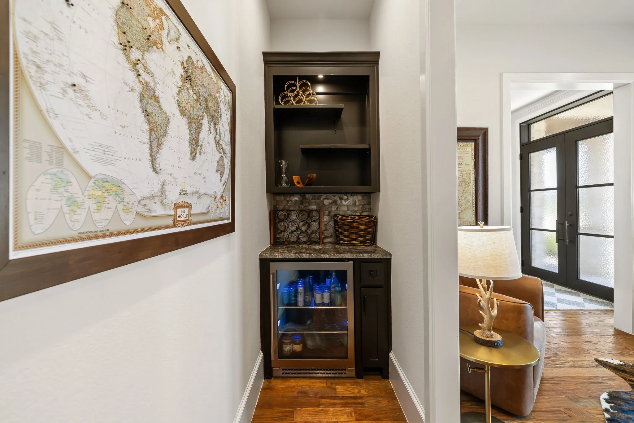 Integrated wet bar featuring dark cabinetry, open shelving, stone backsplash, and an under-counter beverage refrigerator
