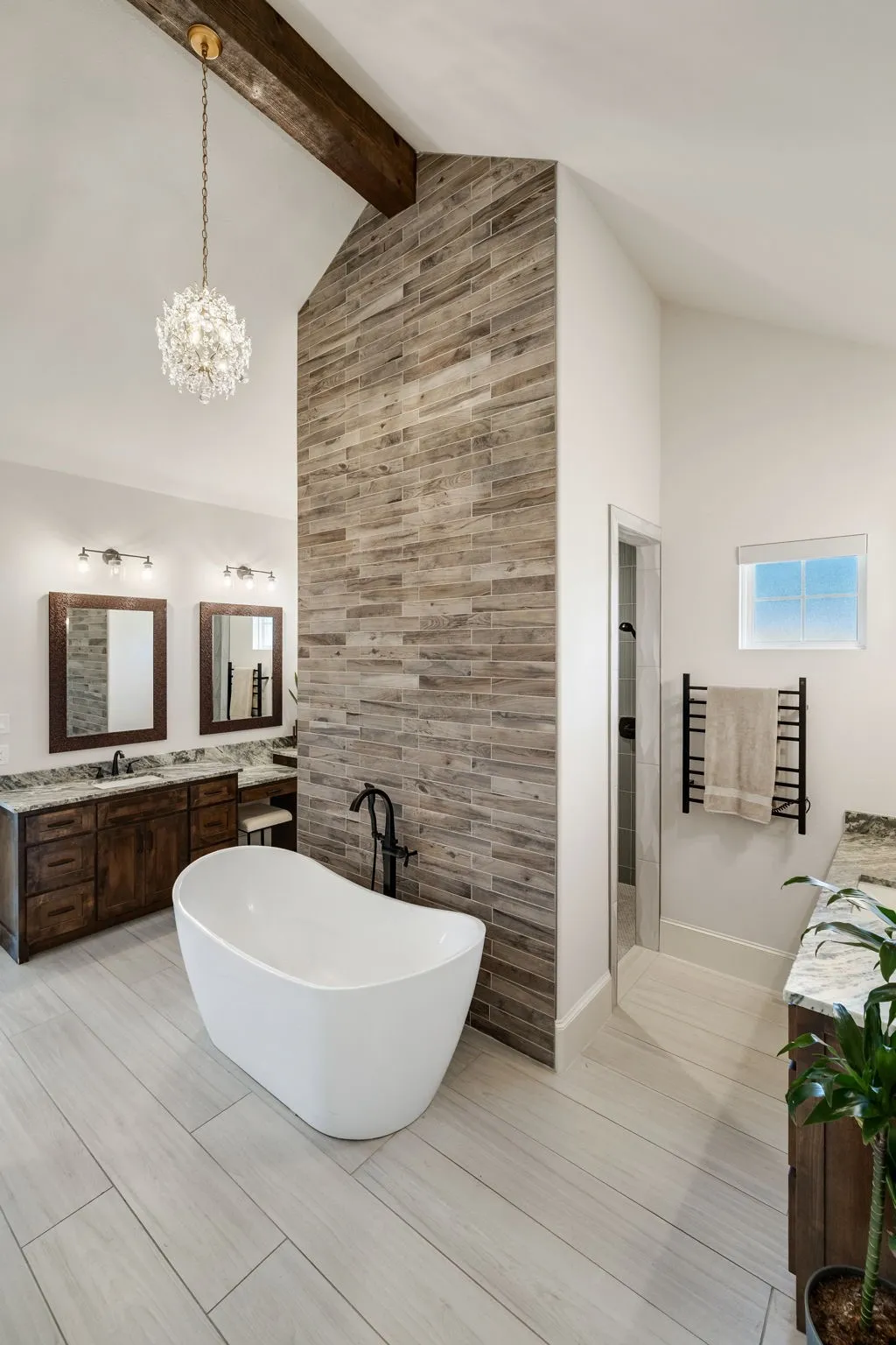 Freestanding soaking tub with a floor-mounted matte black faucet, set against a textured wood-look accent wall