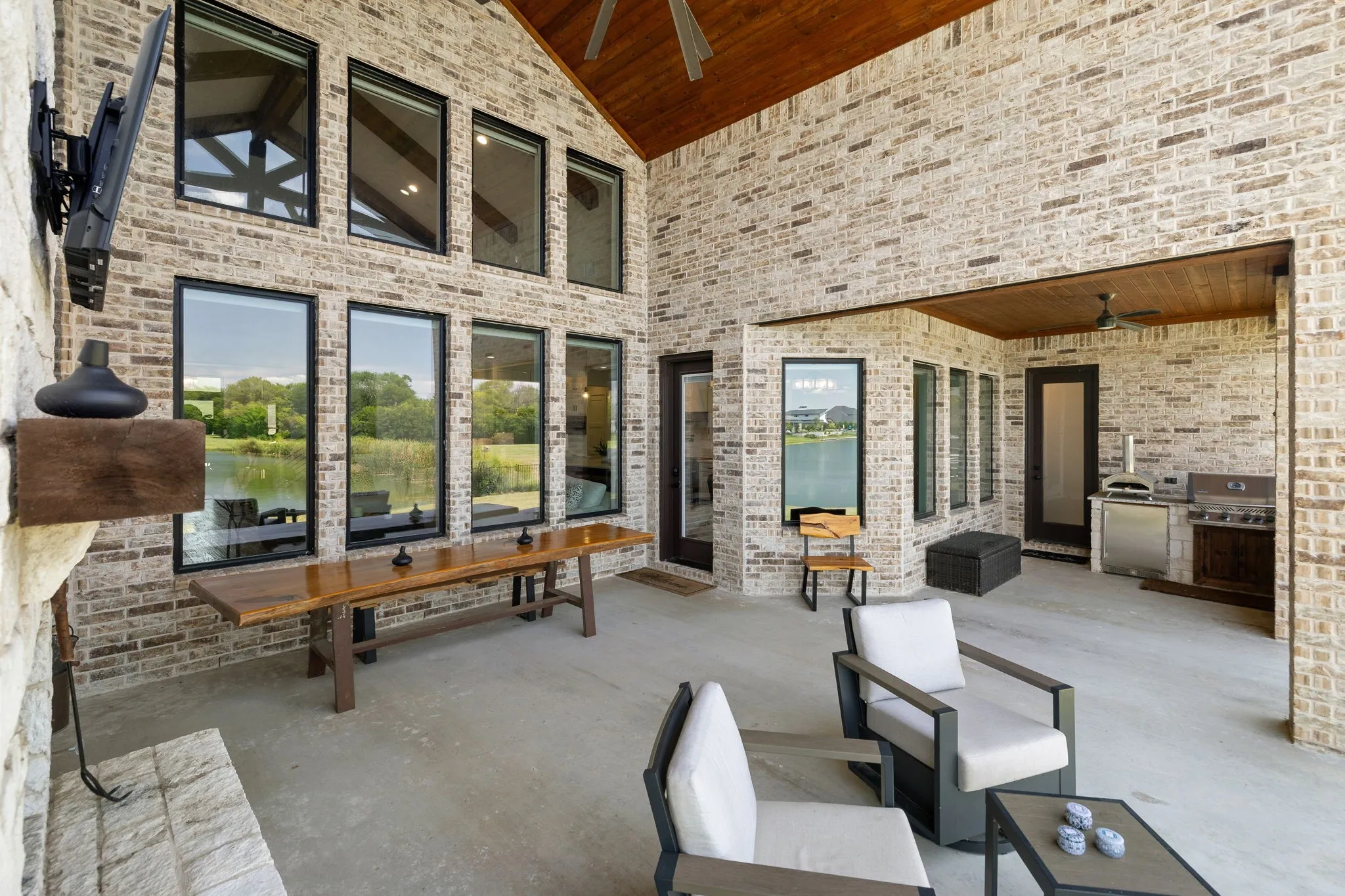 Covered patio with a stone fireplace, wood mantel, and built-in television mount