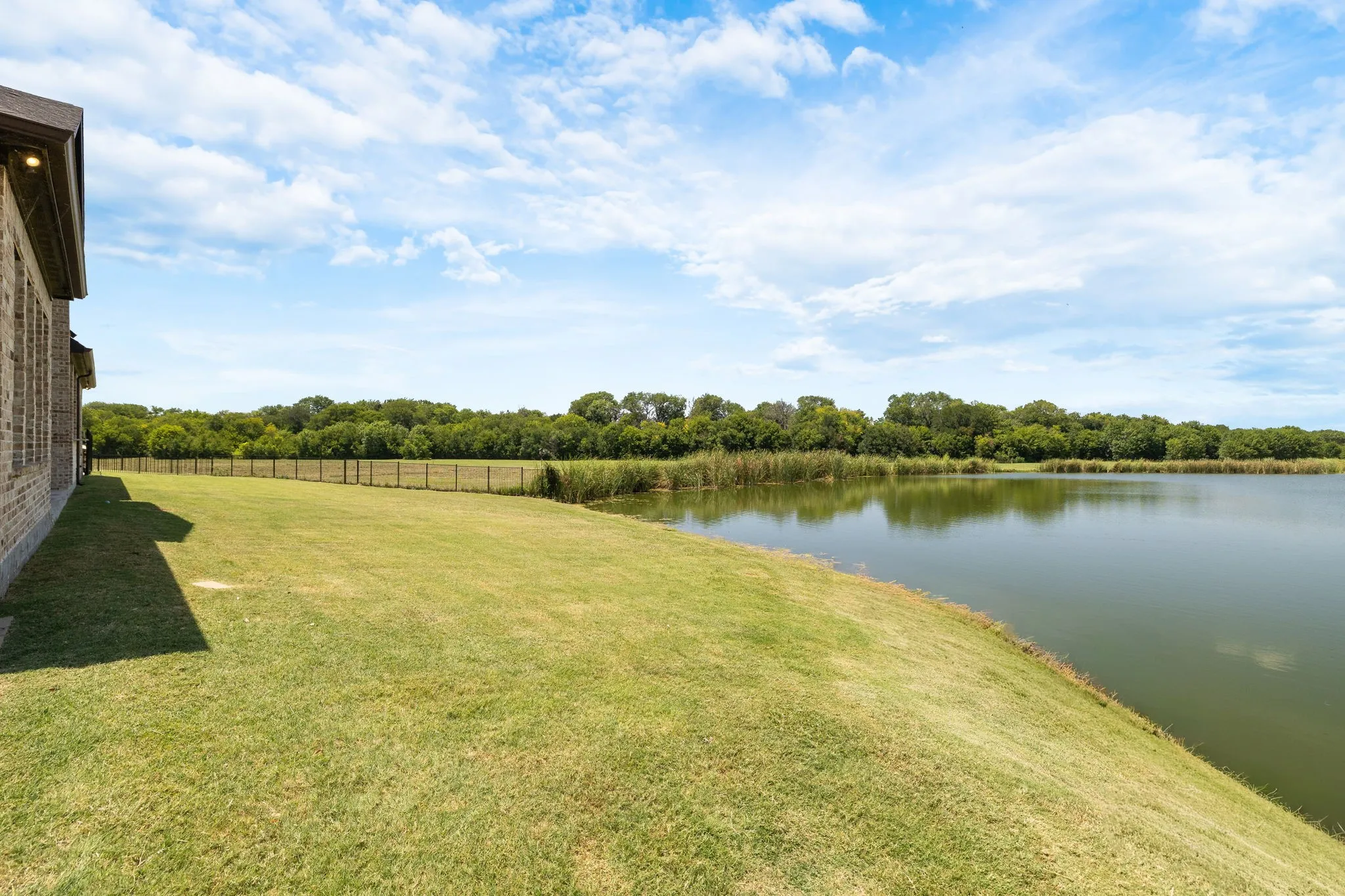 Manicured green lawn bordering a calm body of water with a fountain