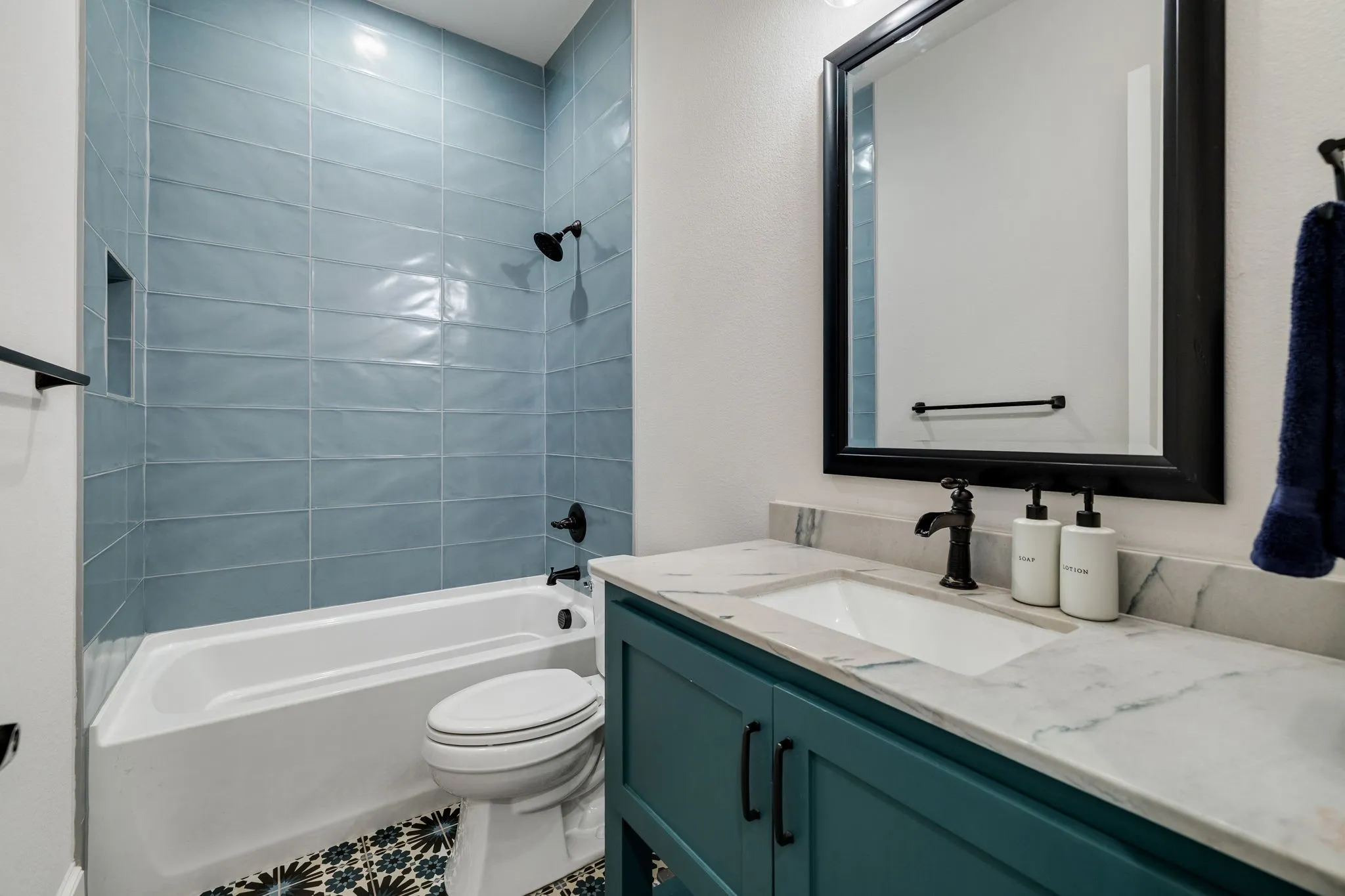 Bonus downstairs bathroom featuring a teal vanity with a stone-finish countertop, undermount sink, and matte black fixtures