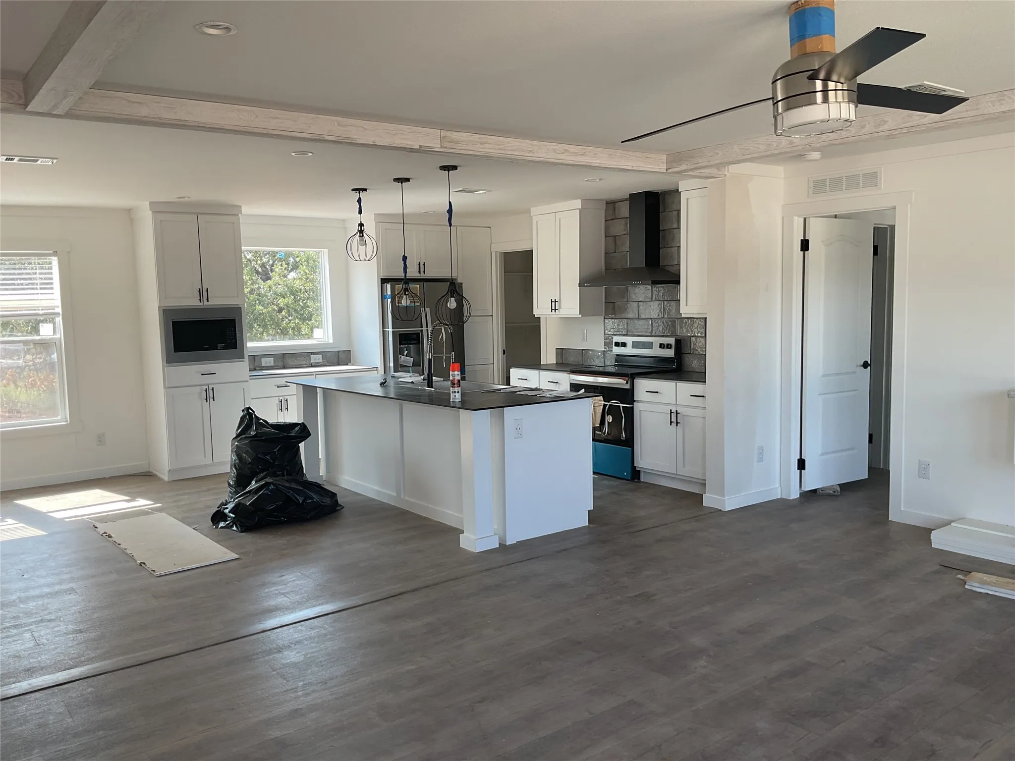 Kitchen featuring white cabinetry, a central island with dark countertop, stainless steel appliances, and wood-finish flooring