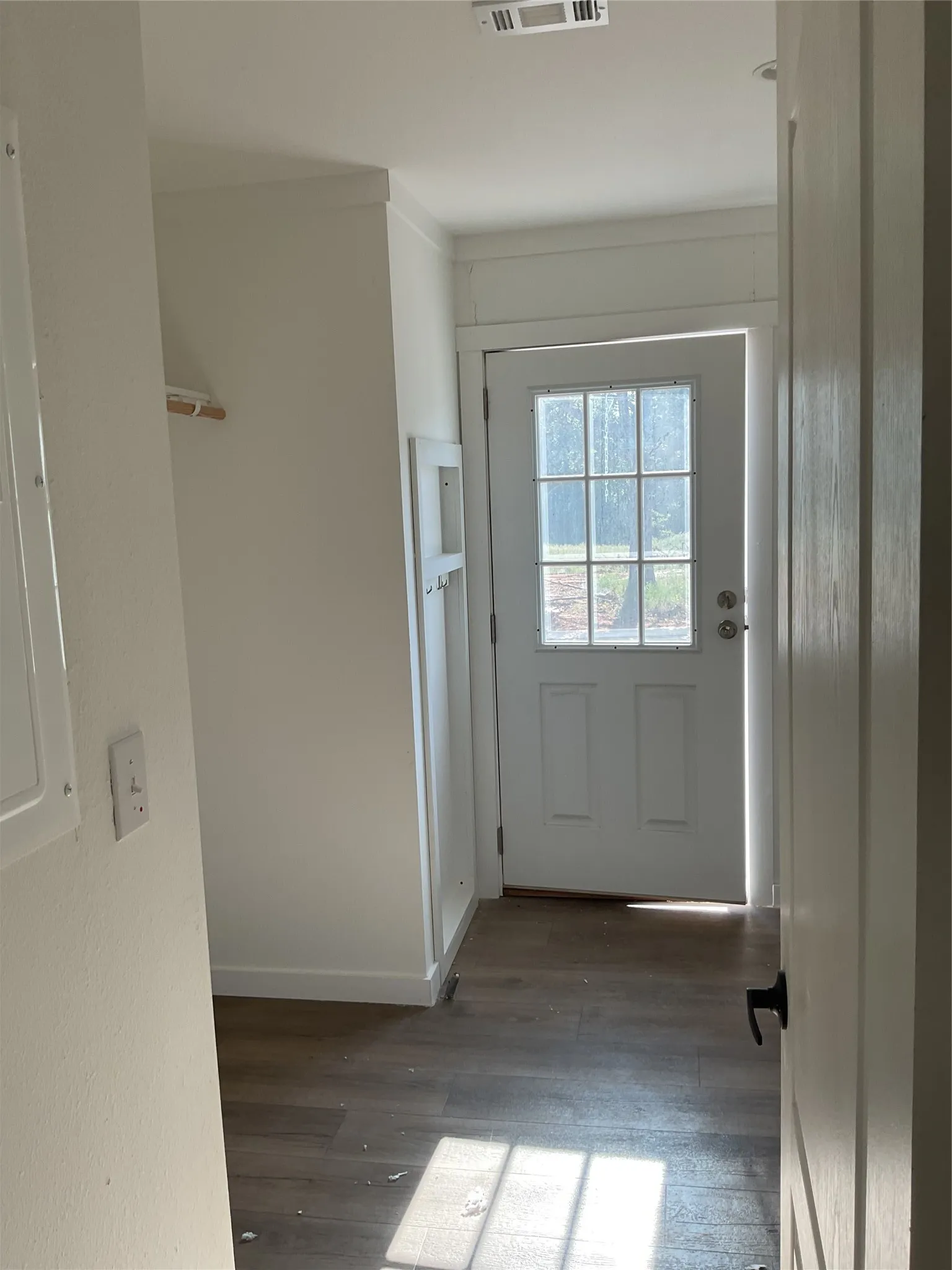 Entry area featuring a white paneled door with glass inserts, wood-finish flooring, white baseboards, and crown molding