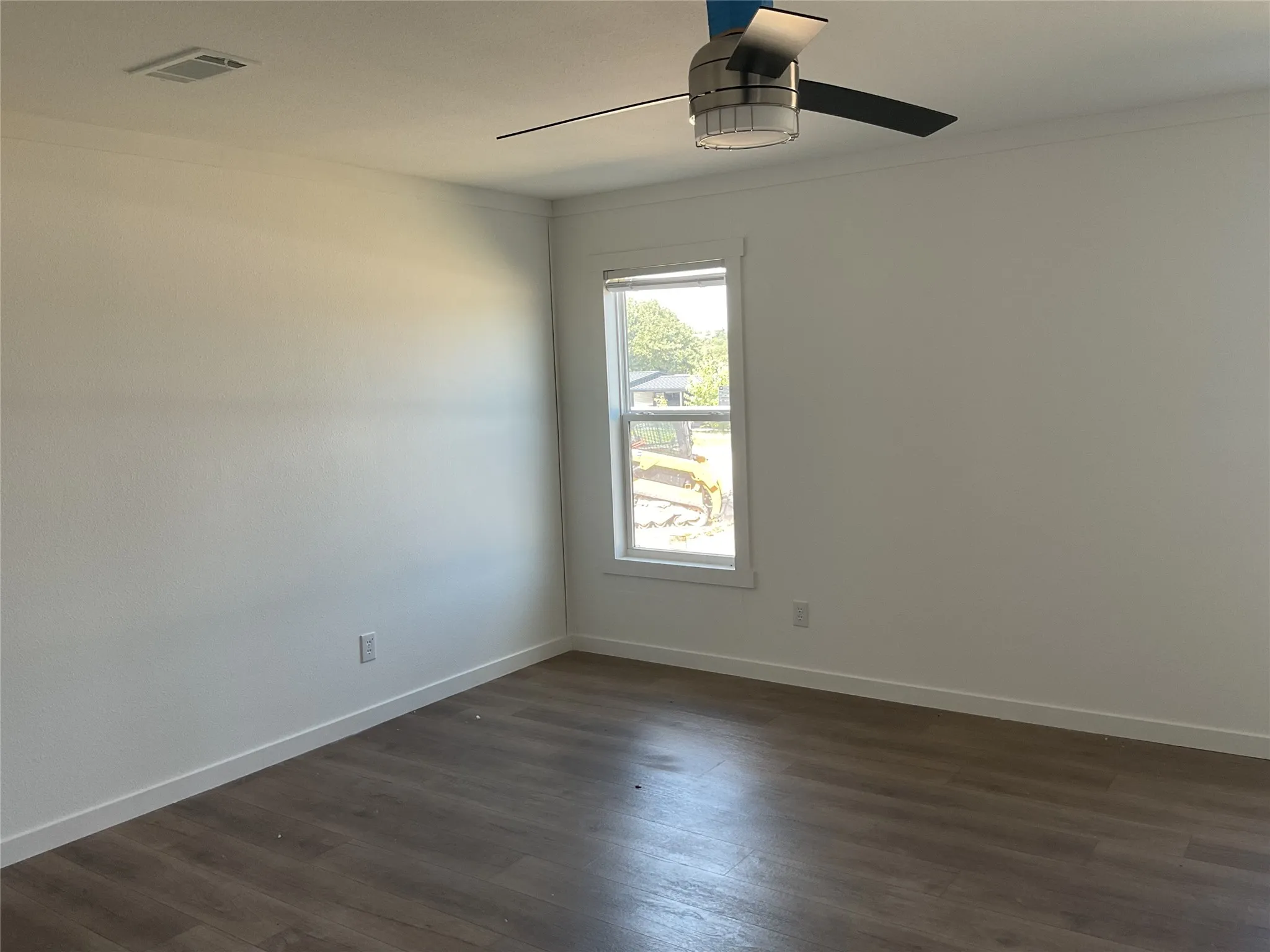 Wood-finish flooring, white walls, and a modern ceiling fan with integrated lighting