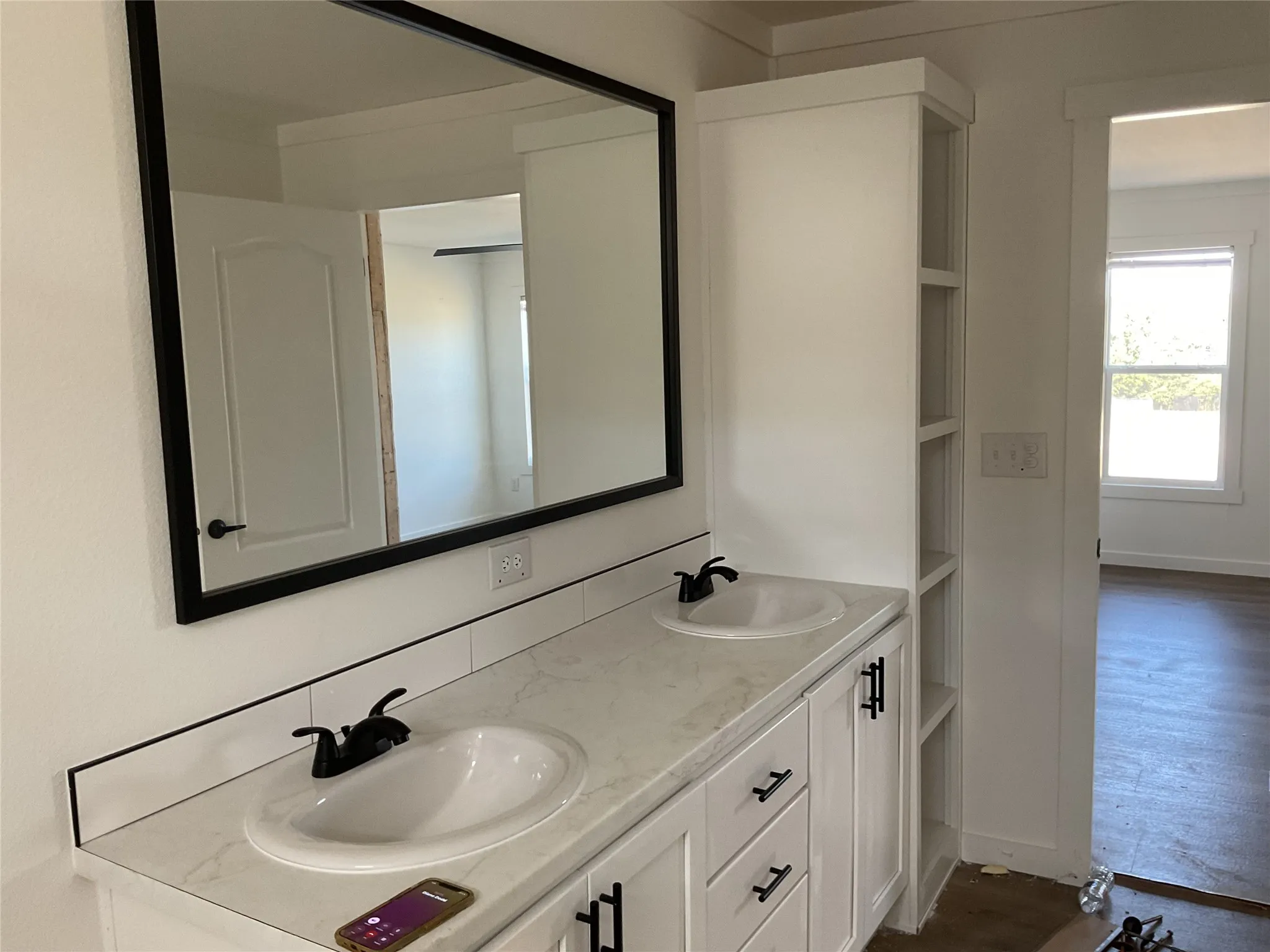 Dual vanity featuring white shaker cabinetry, matte black hardware, and a stone-finish countertop with integrated sinks