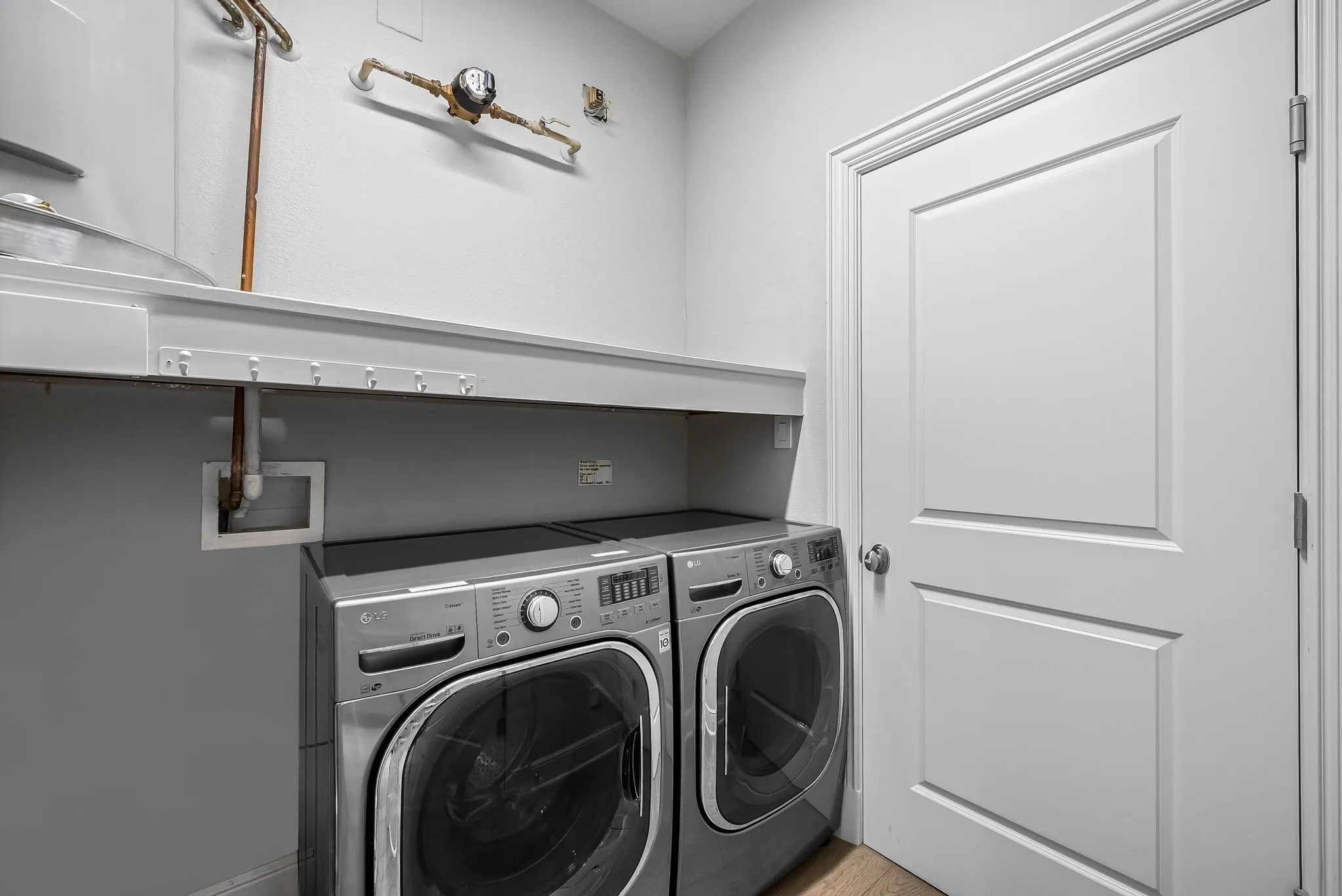 Utility room featuring a paneled door, built-in shelving, and a hanging rack