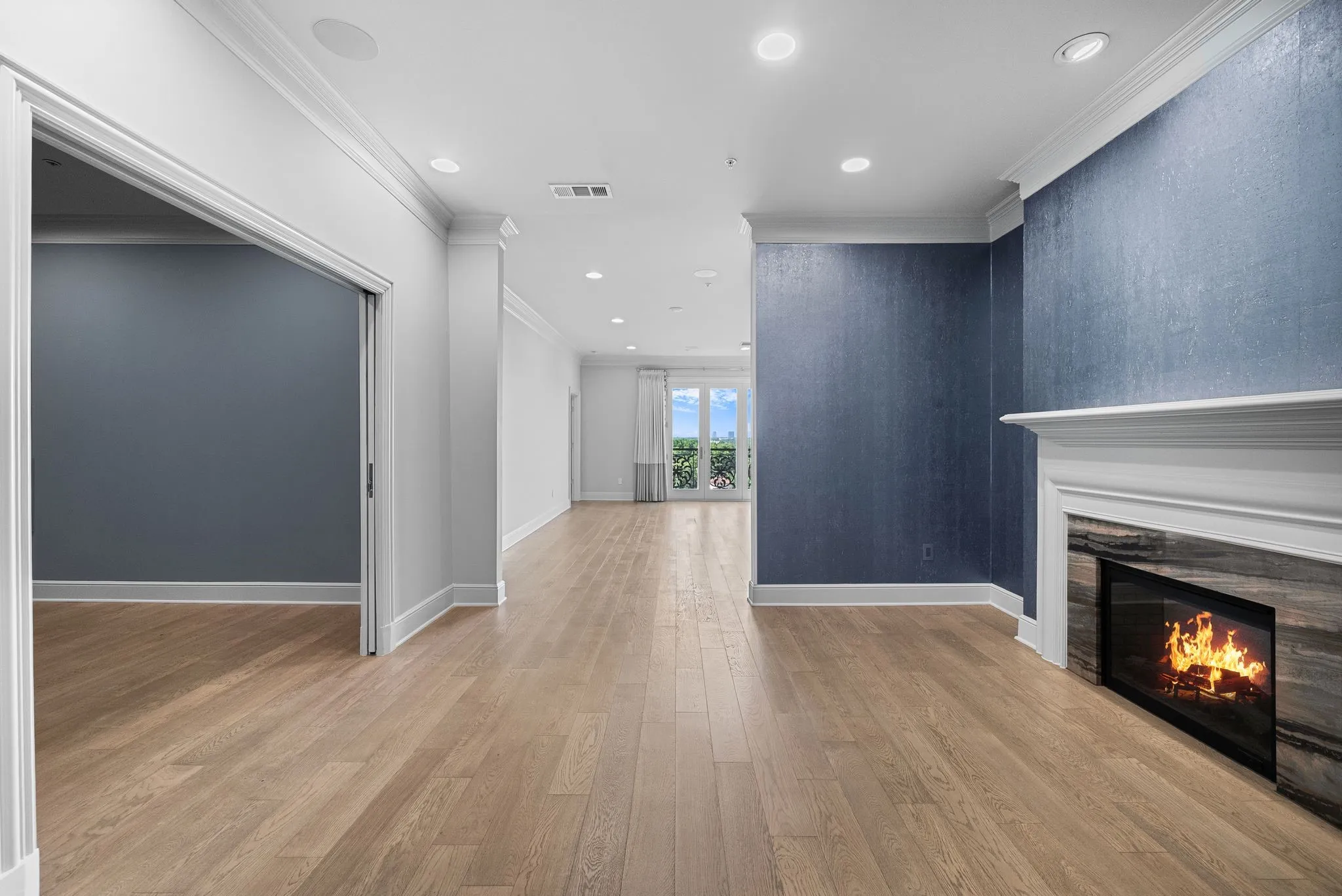 Spacious interior featuring wood-finish flooring, a contemporary fireplace with stone surround and white mantel, recessed lighting, and a textured accent wall