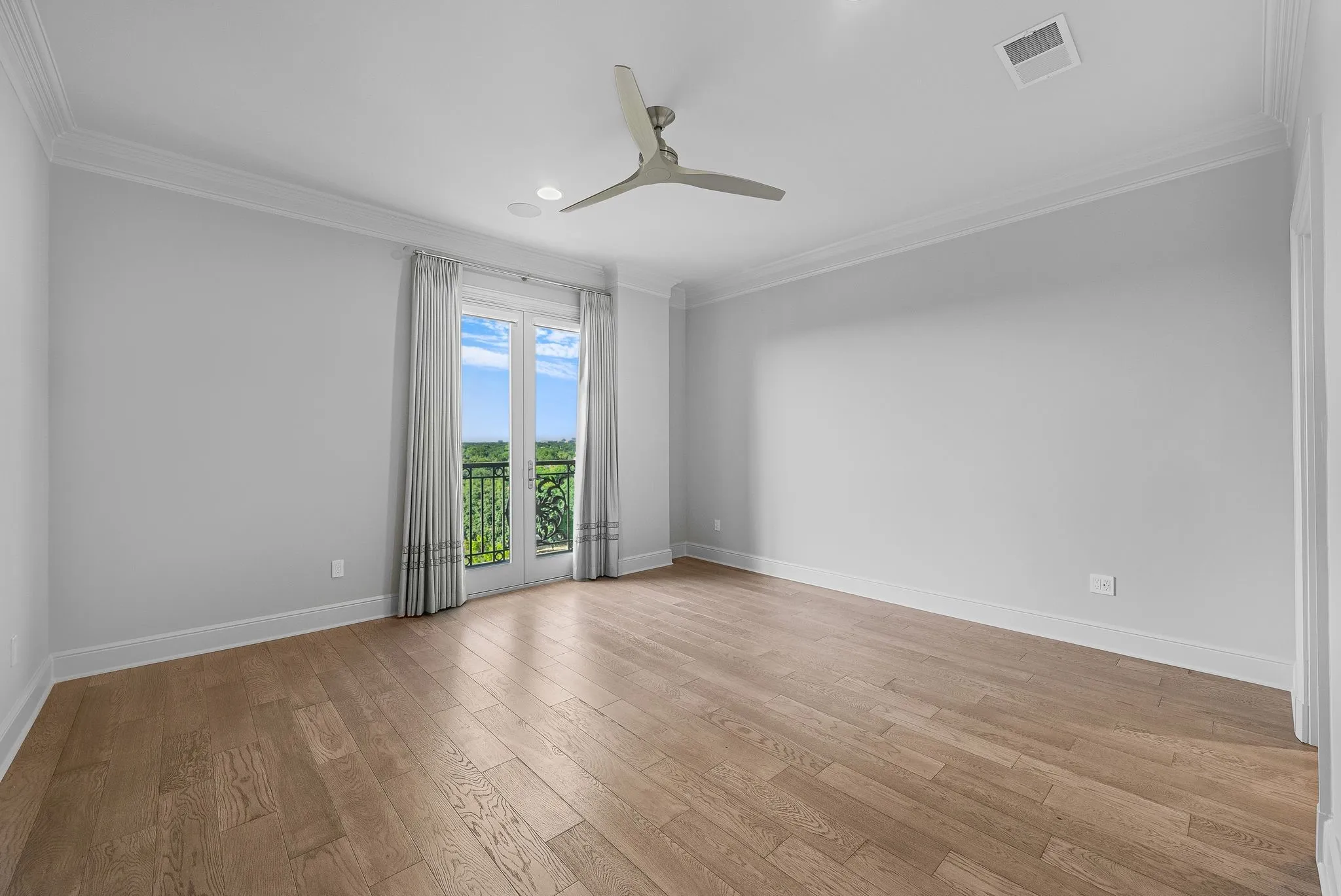 Light-filled room featuring wood-finish flooring, a ceiling fan, recessed lighting, and crown molding