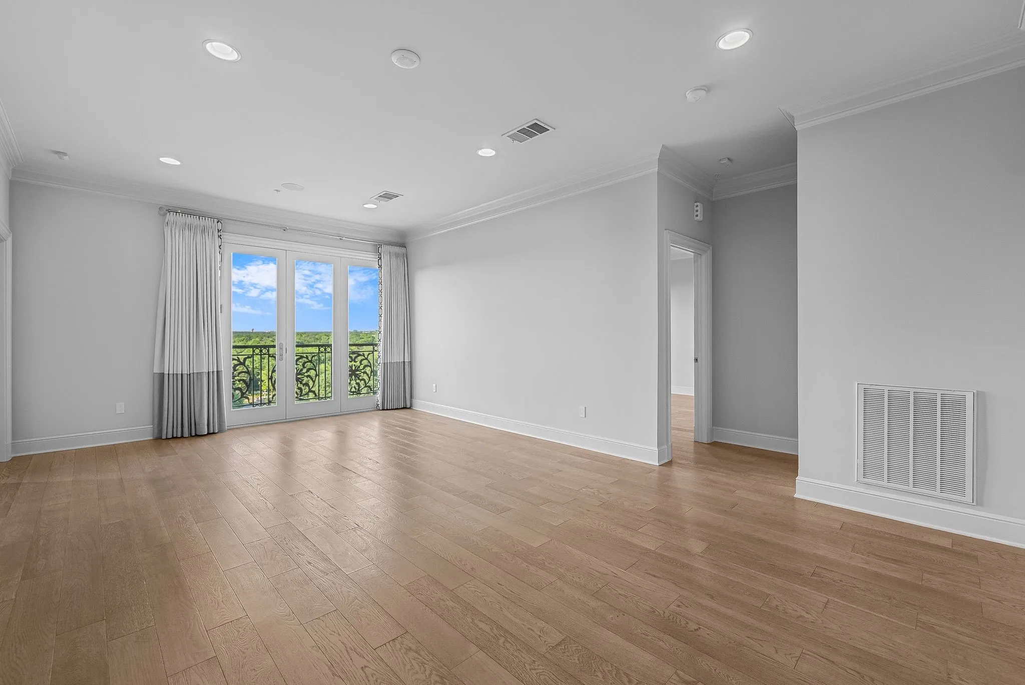 Spacious room featuring light wood-finish flooring, recessed lighting, and crown molding