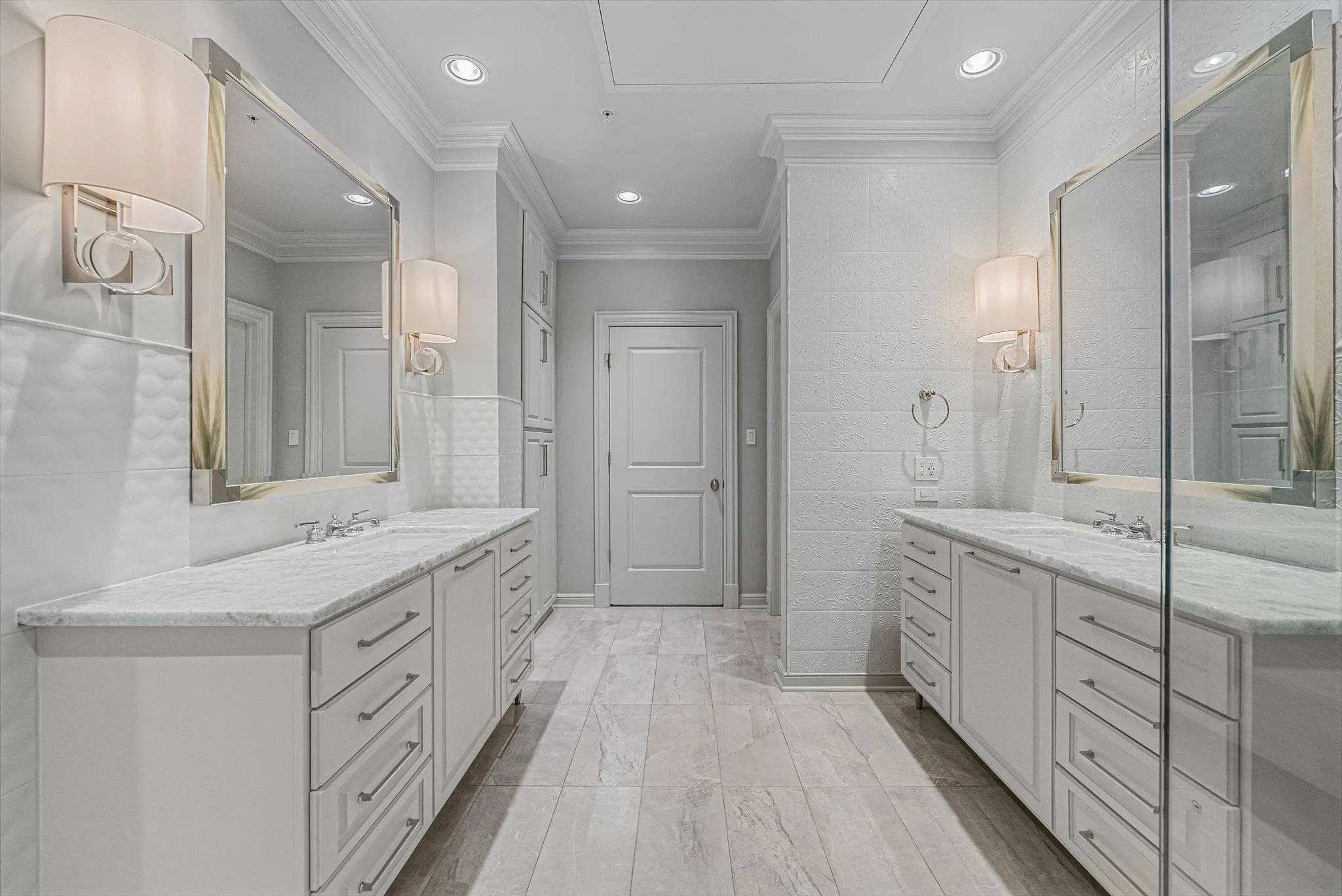 Spacious bathroom featuring dual vanities with stone countertops, ample cabinet and drawer storage, framed mirrors, and wall sconces