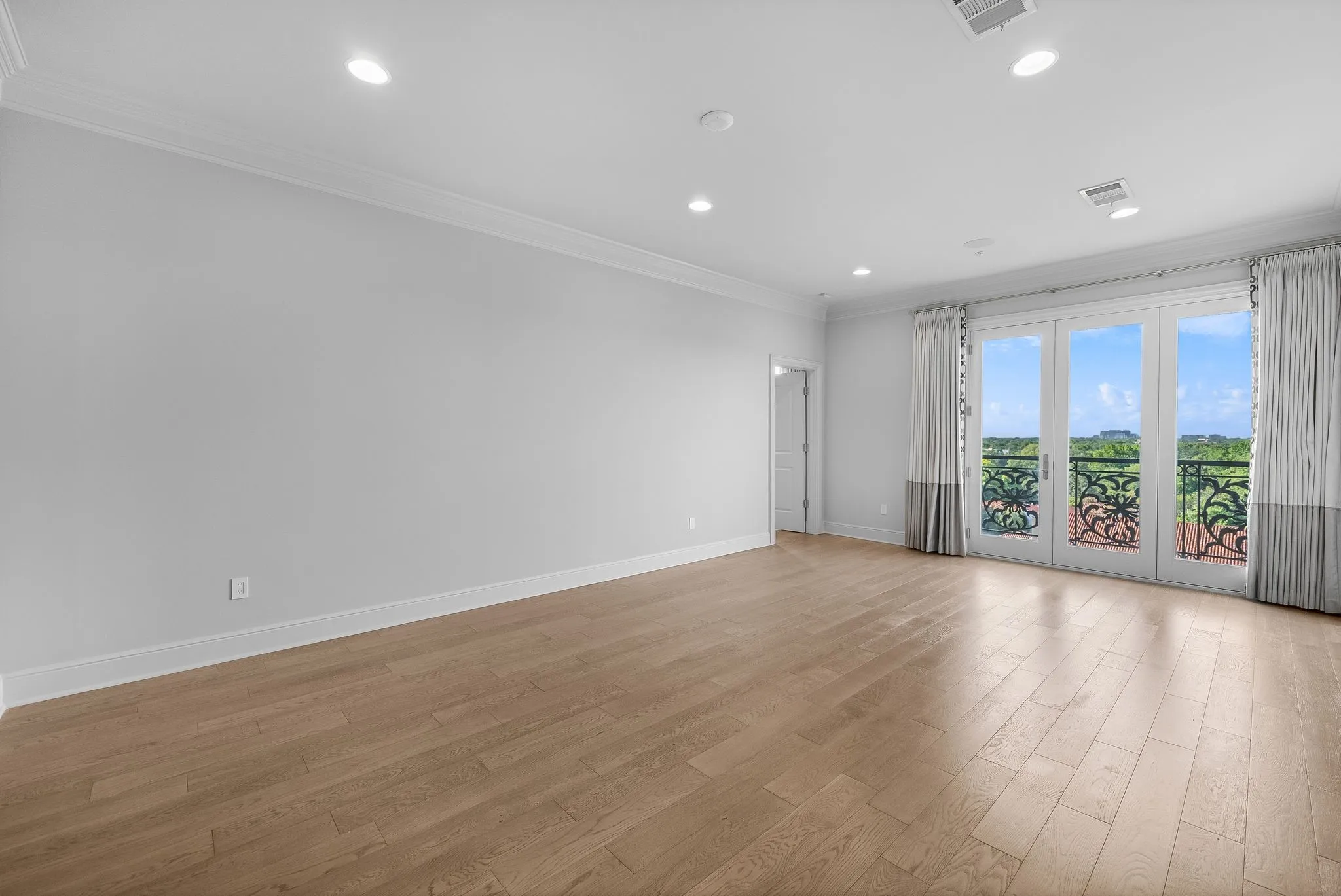 Spacious room featuring wood-finish flooring, recessed lighting, and crown molding
