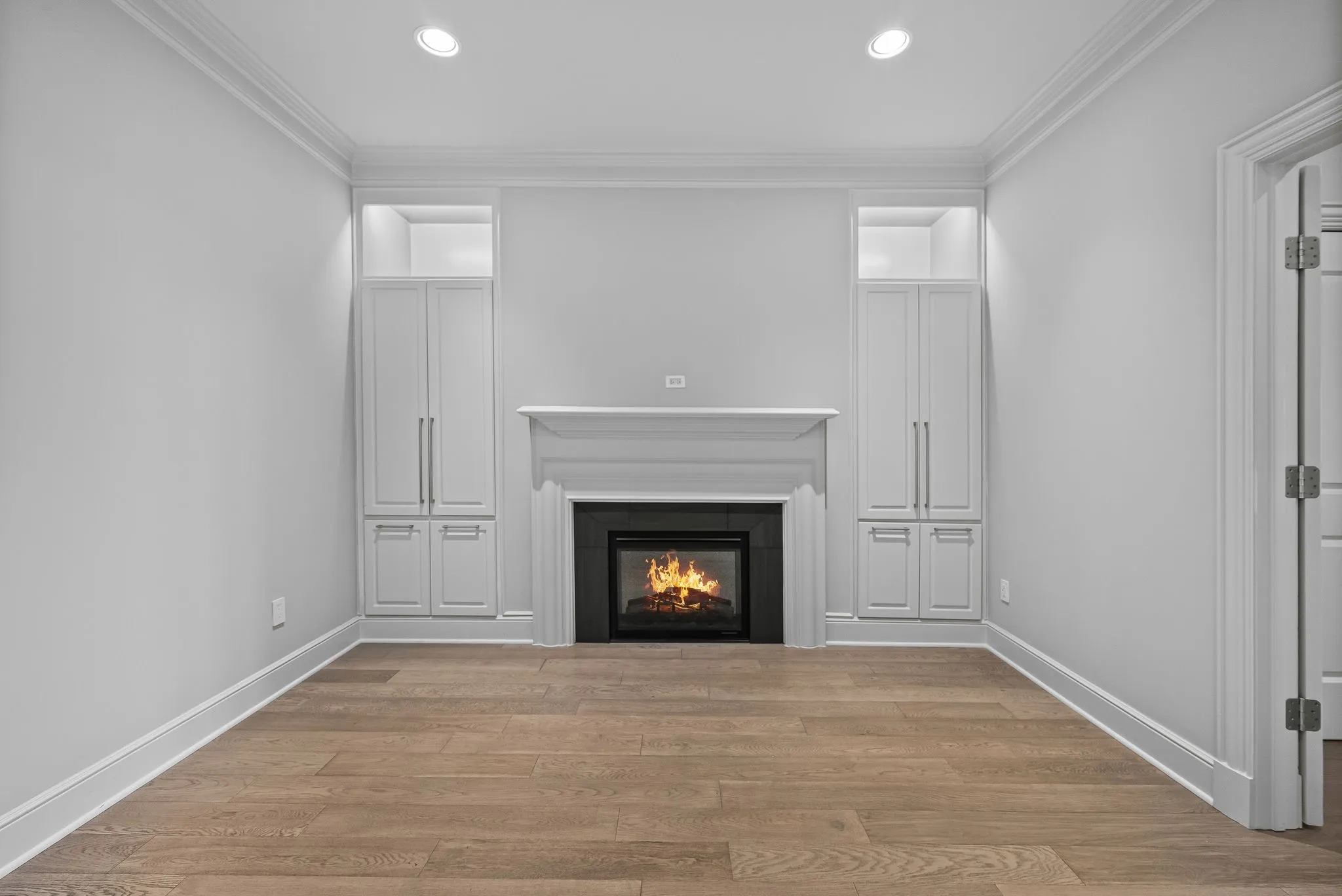 Centrally located fireplace with a white mantel, flanked by built-in cabinetry with integrated shelving and recessed lighting