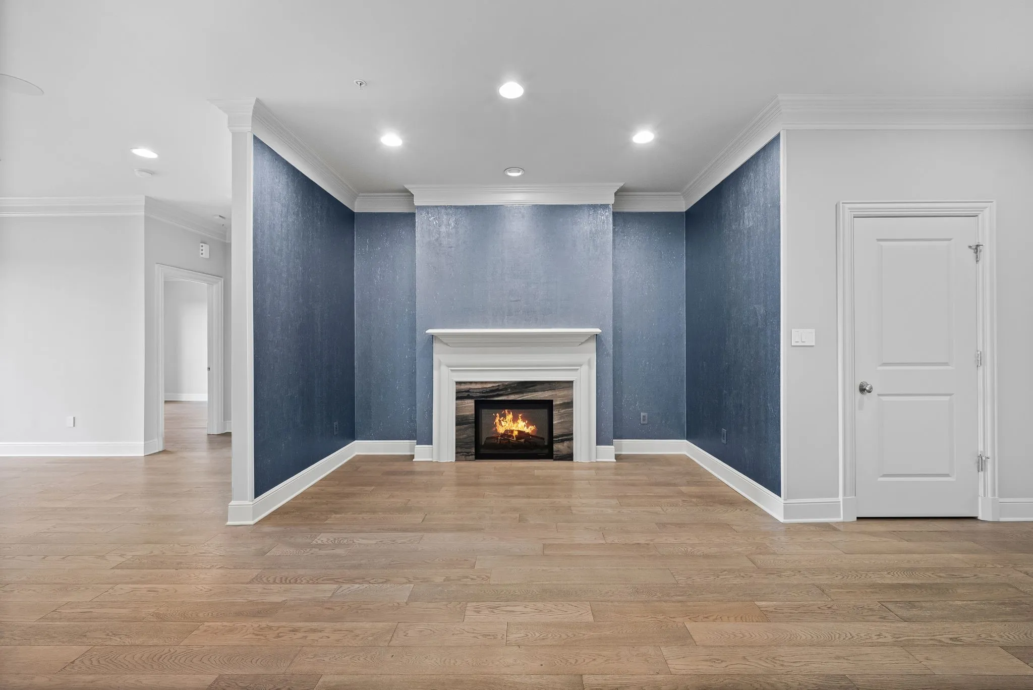 Hardwood-style flooring throughout this room, featuring a fireplace with a white mantel and stone surround