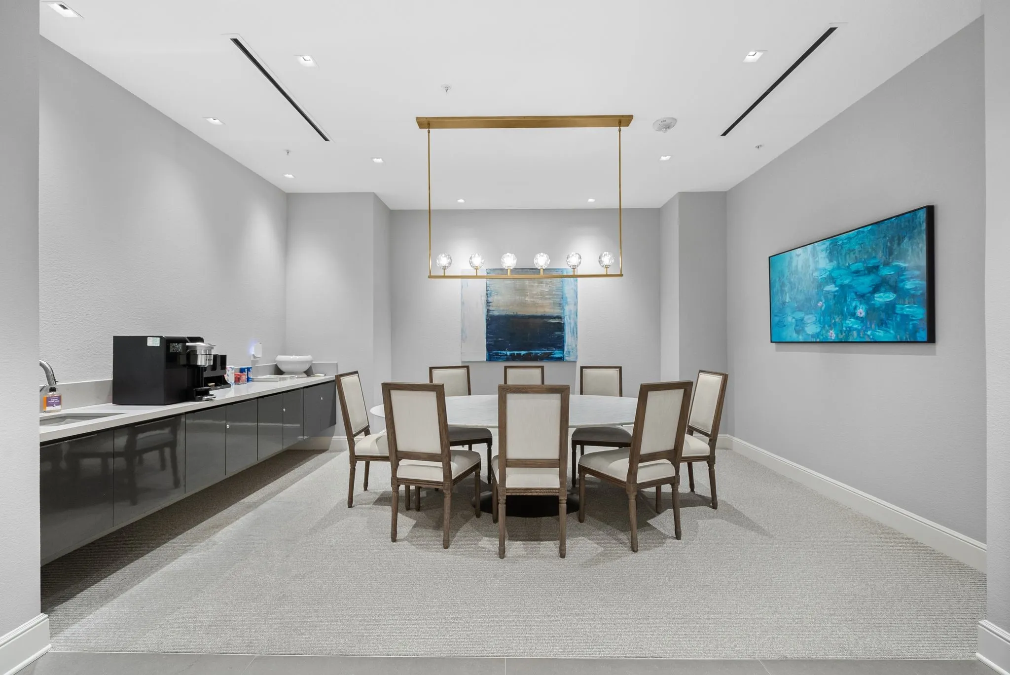 Dedicated meeting room featuring recessed lighting, a linear brass chandelier, and a built-in refreshment bar with a sink and ample counter space