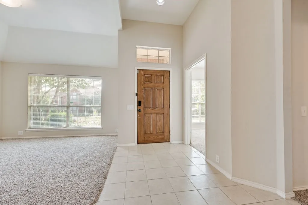 Entryway featuring a paneled wood door, transom window, and tile flooring