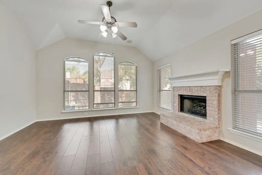 Spacious room featuring rich wood-finish flooring and a vaulted ceiling and gas fireplace