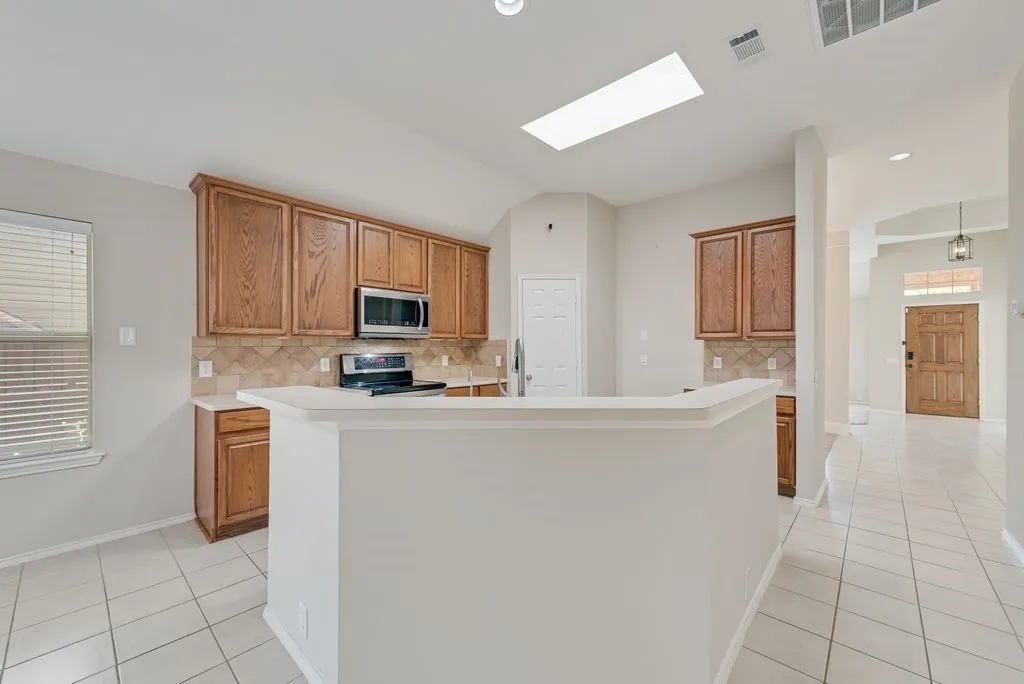Kitchen with wood cabinetry, stainless steel appliances, and a breakfast bar