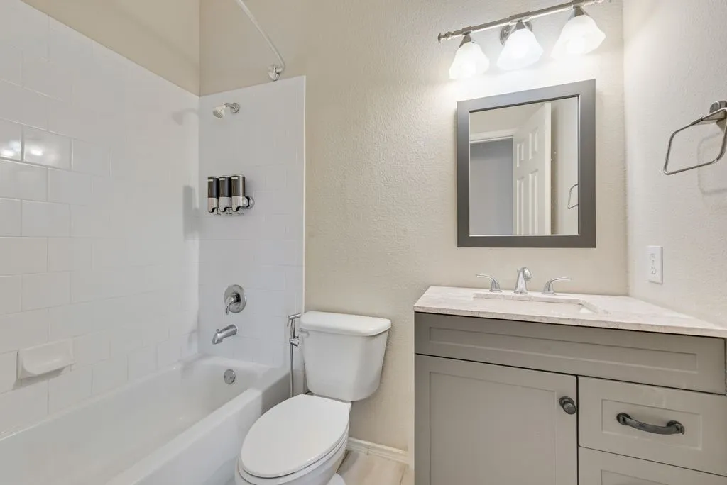 Bathroom featuring a corner vanity with a light-toned countertop, a framed mirror, and a three-light fixture