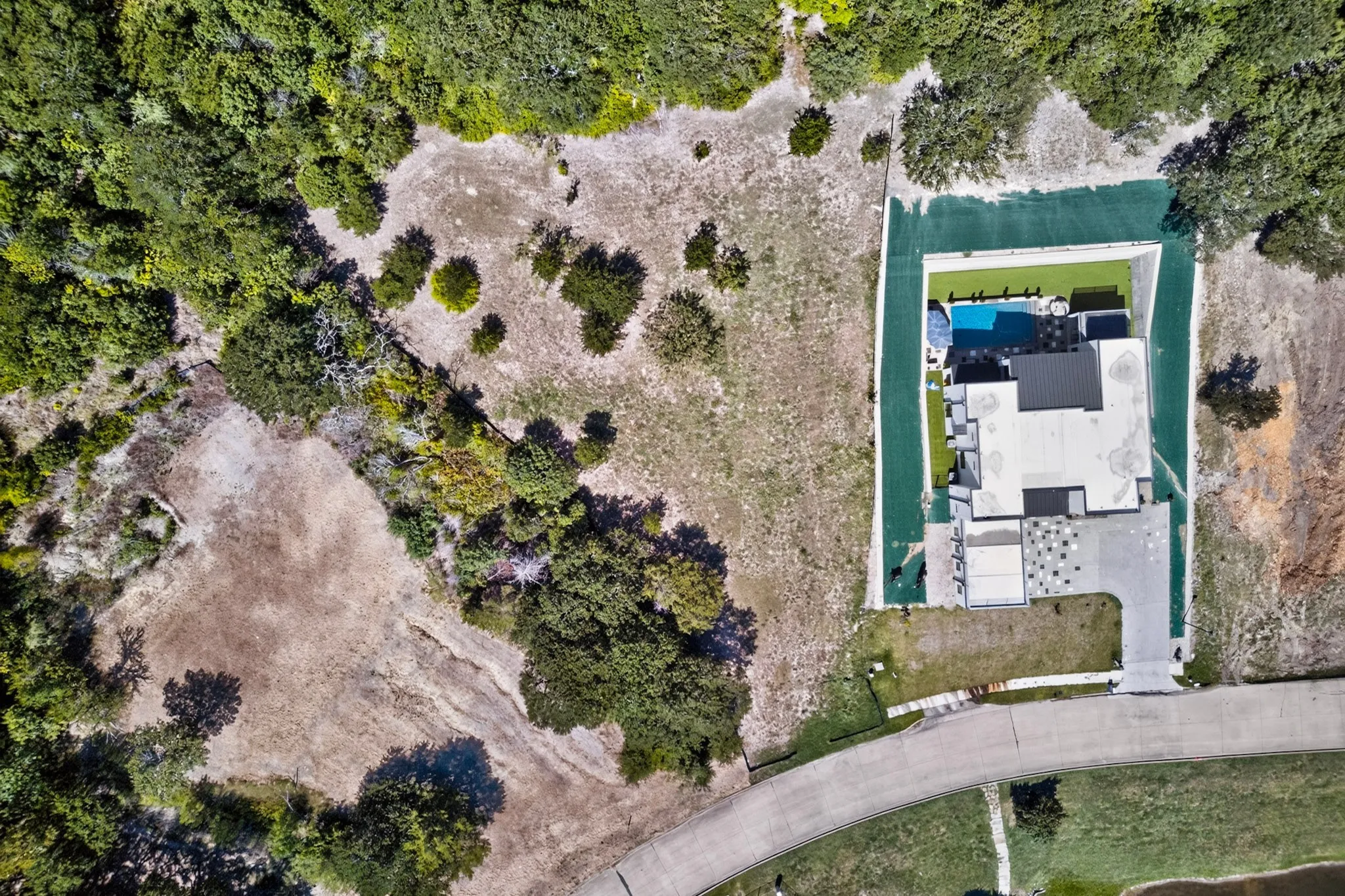 Modern residence featuring a rectangular swimming pool, artificial turf landscaping, and an expansive paved driveway