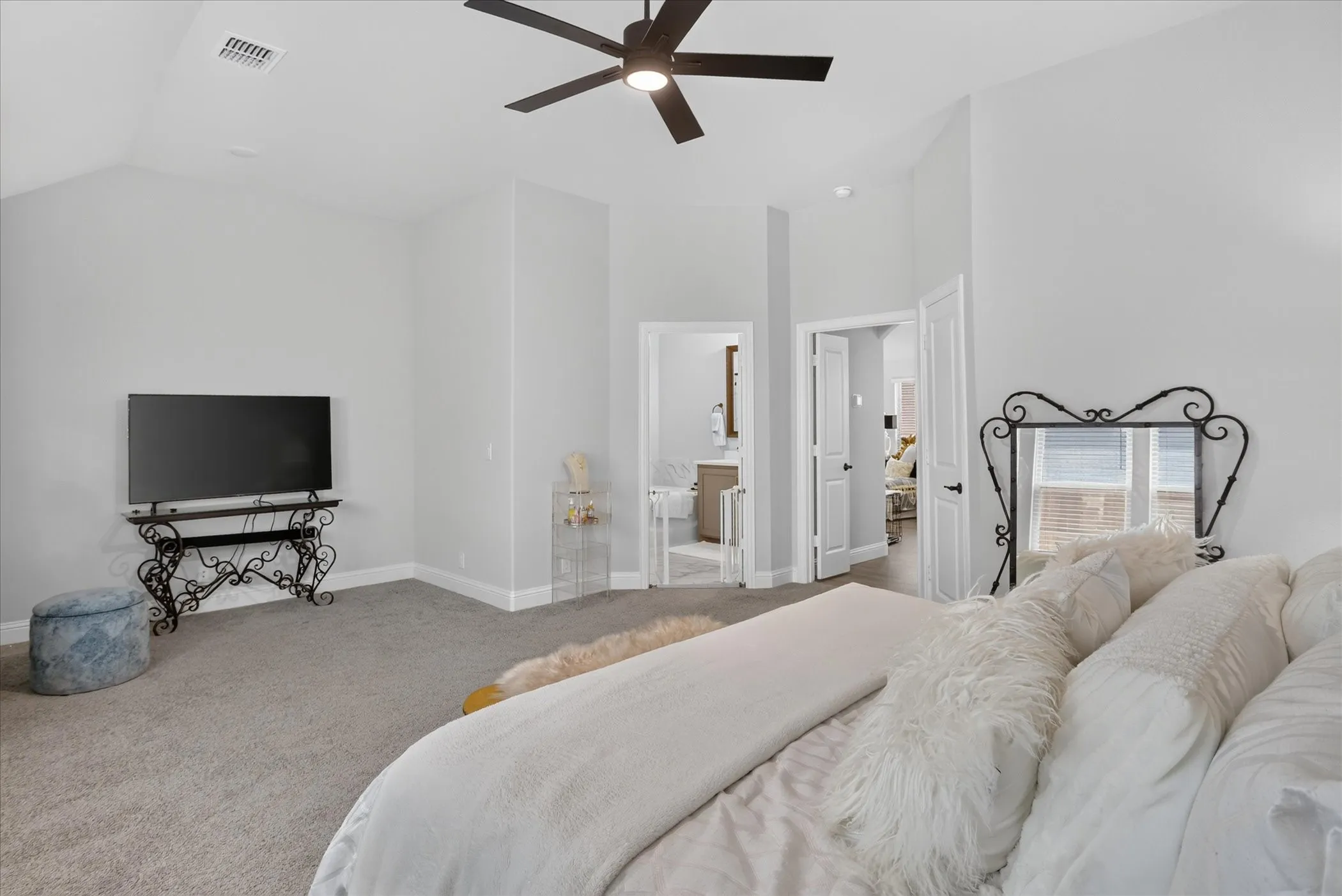 Spacious room featuring vaulted ceilings, ceiling fan, and carpet flooring