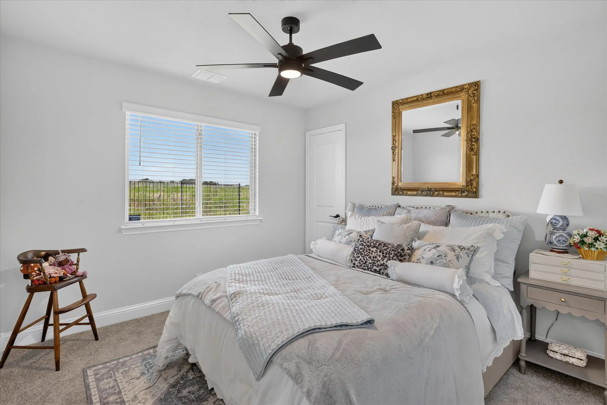 Spacious room featuring a large window, a ceiling fan with integrated lighting, neutral-toned walls, and carpet flooring