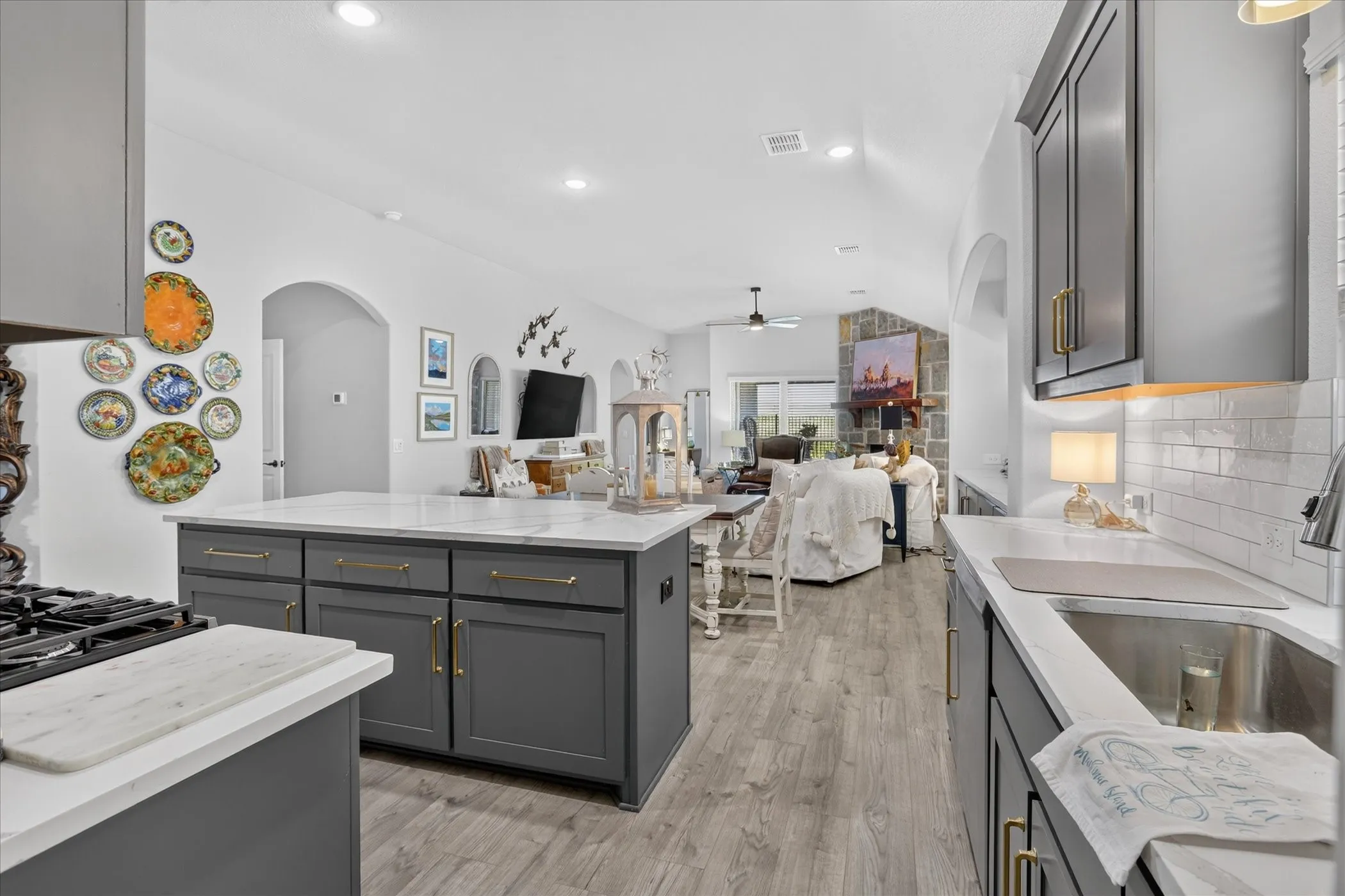 Modern kitchen featuring gray cabinetry, light countertops, wood-finish flooring, and an open concept layout