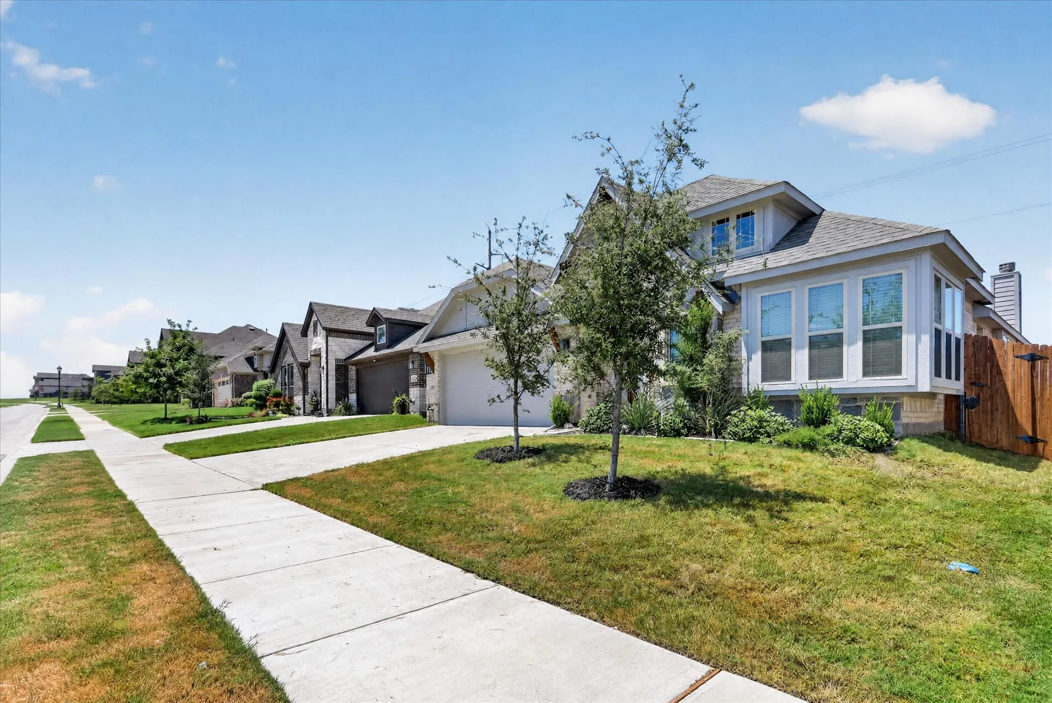 Contemporary two-story residence featuring a bay window, natural stone accents, and a two-car garage