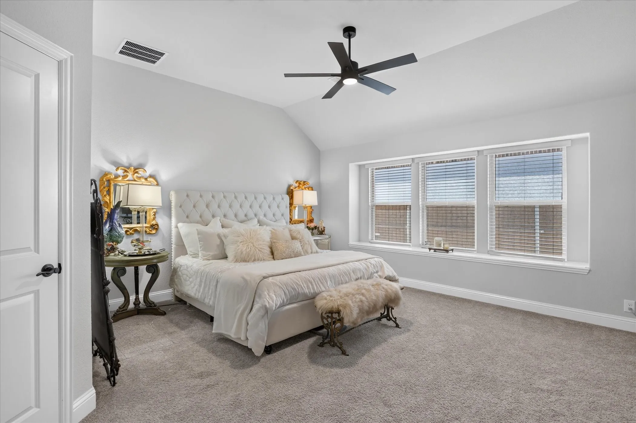 Bedroom featuring vaulted ceiling, carpeted flooring, three large windows with blinds, and a contemporary ceiling fan